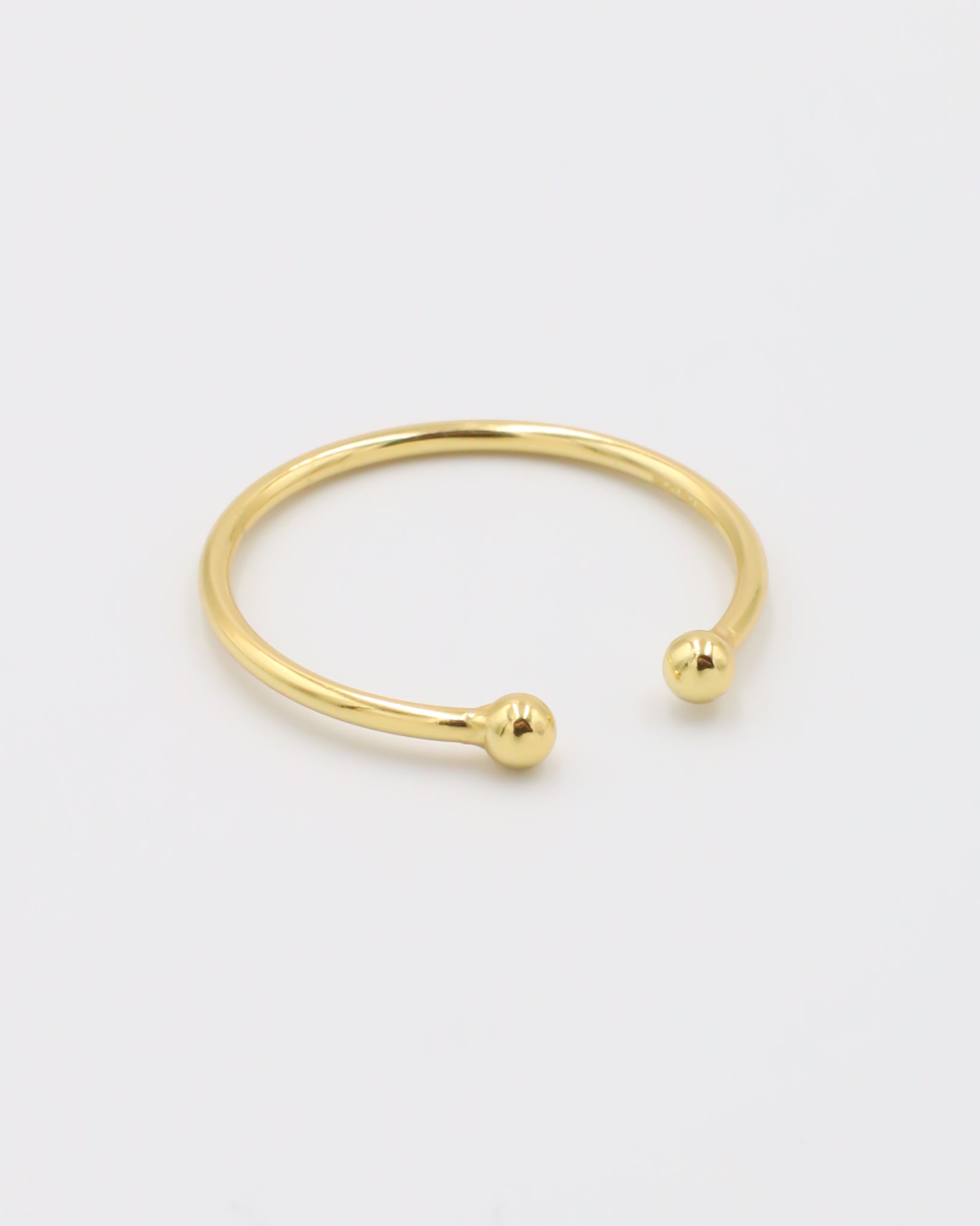 A simple gold-colored ring with two spherical decorations, displayed against a white background.