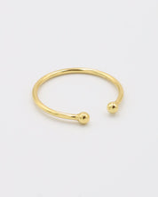 A simple gold-colored ring with two spherical decorations, displayed against a white background.
