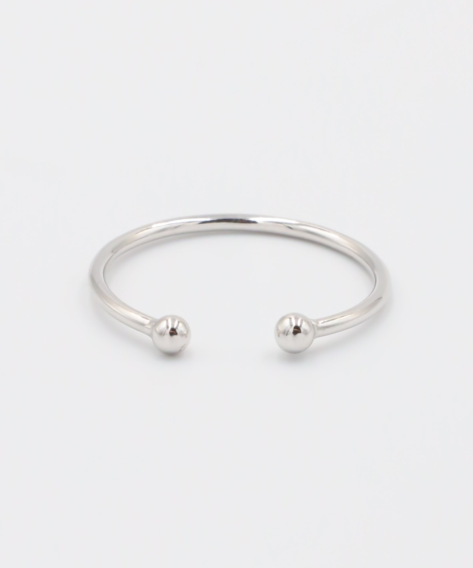 A simple silver bracelet with an adjustable band and small spherical embellishments at the ends.