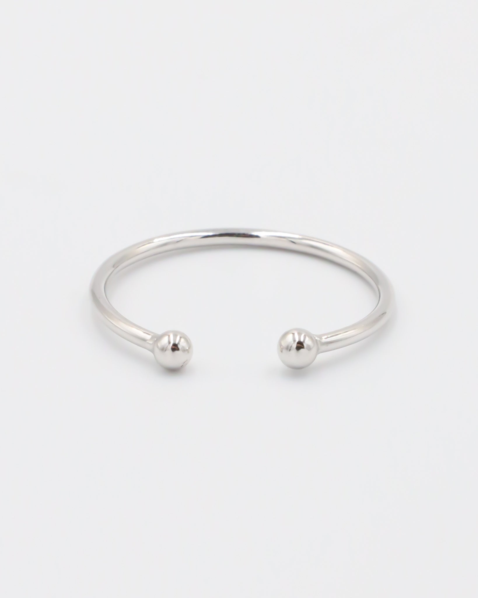 A simple silver bracelet with an adjustable band and small spherical embellishments at the ends.
