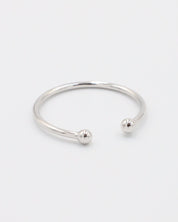 A simple silver bracelet with an adjustable band and small spherical embellishments at the ends.