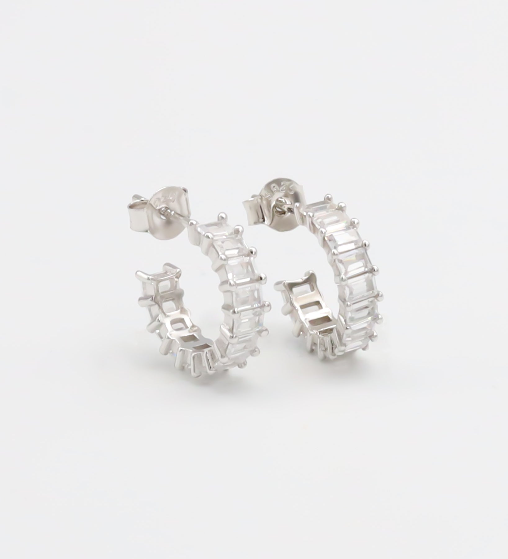 A pair of silver hoop earrings with a textured surface, displayed against a white background.