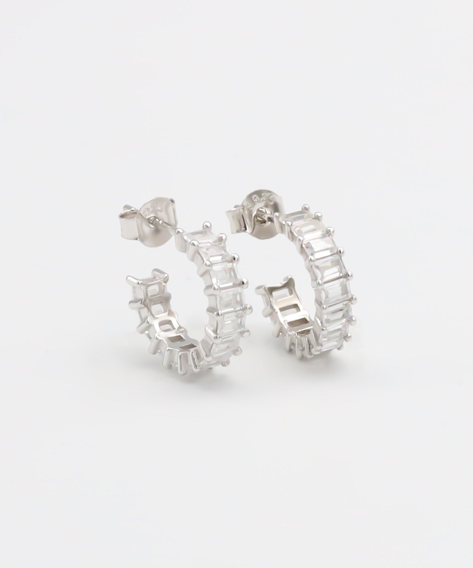A pair of silver hoop earrings with a textured surface, displayed against a white background.