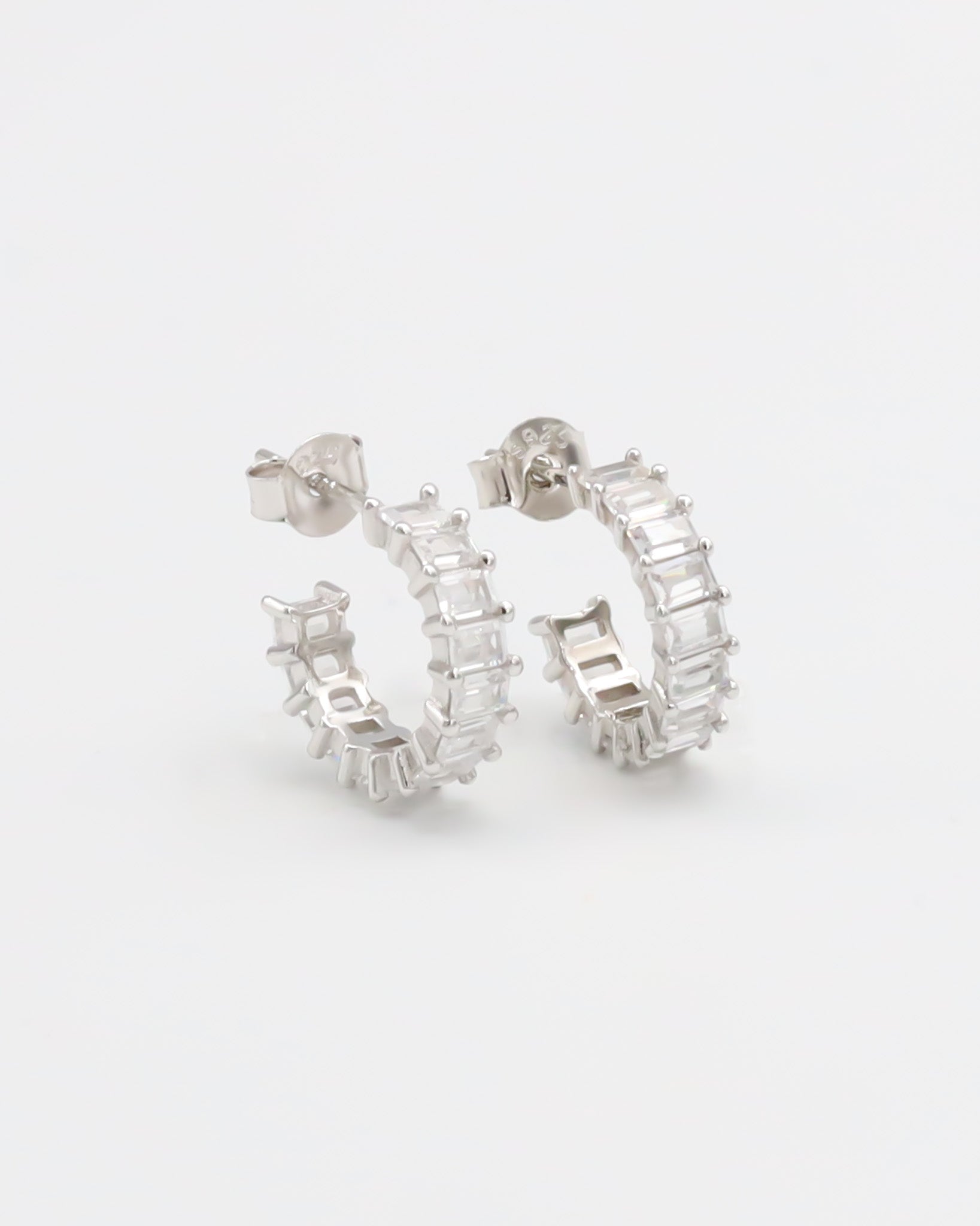 A pair of silver hoop earrings with a textured surface, displayed against a white background.