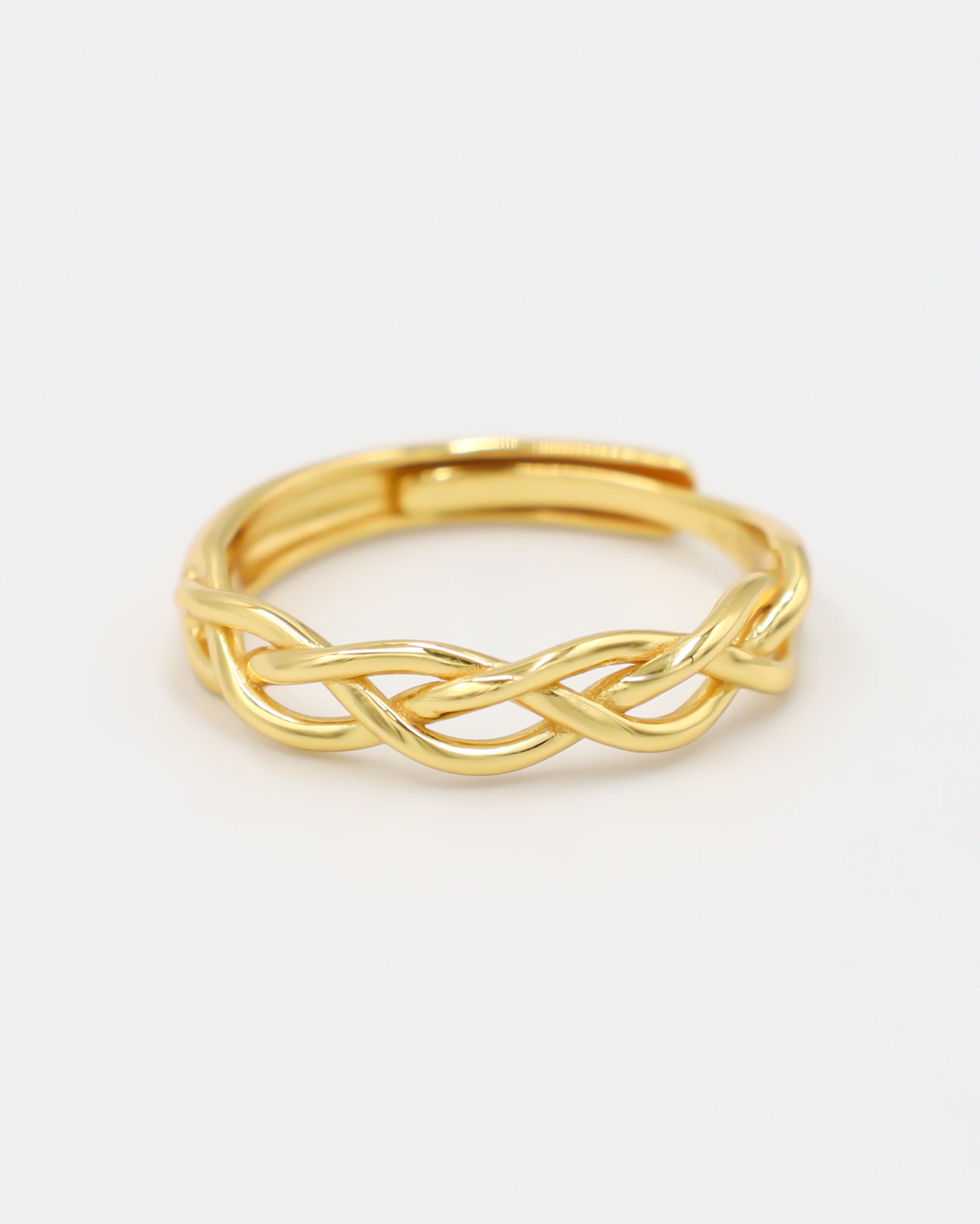 A gold-colored ring with a geometric pattern on a white background