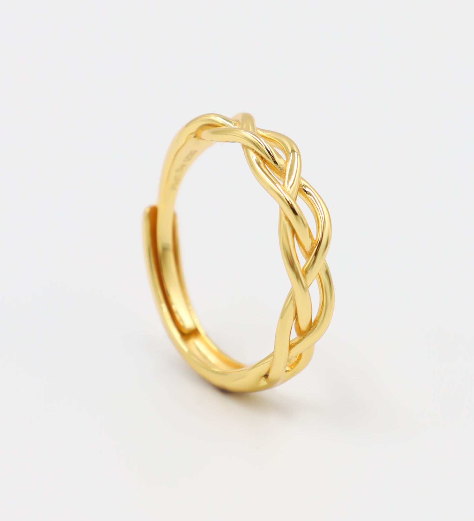 A gold-colored ring with a geometric pattern on a white background
