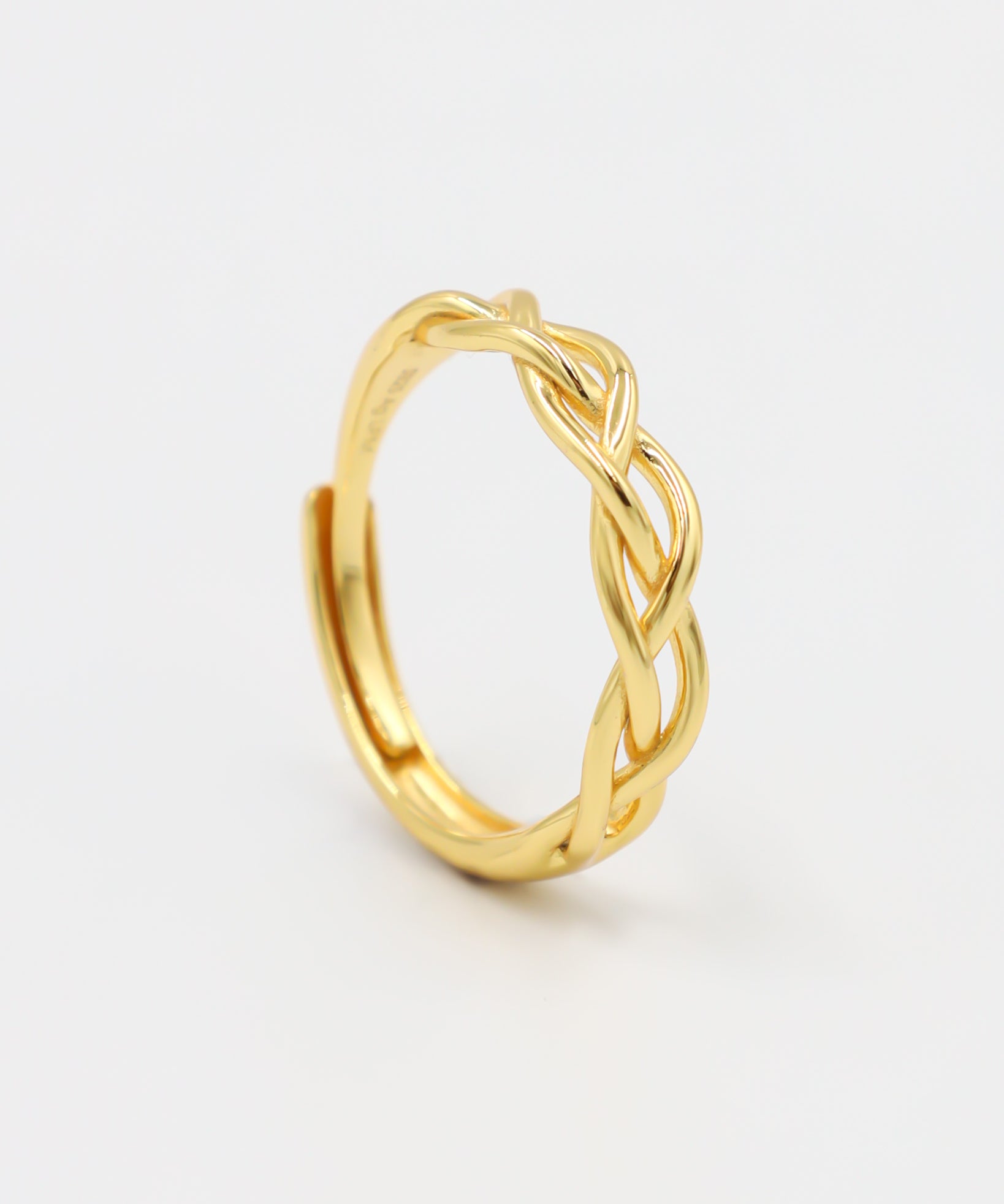 A gold-colored ring with a geometric pattern on a white background