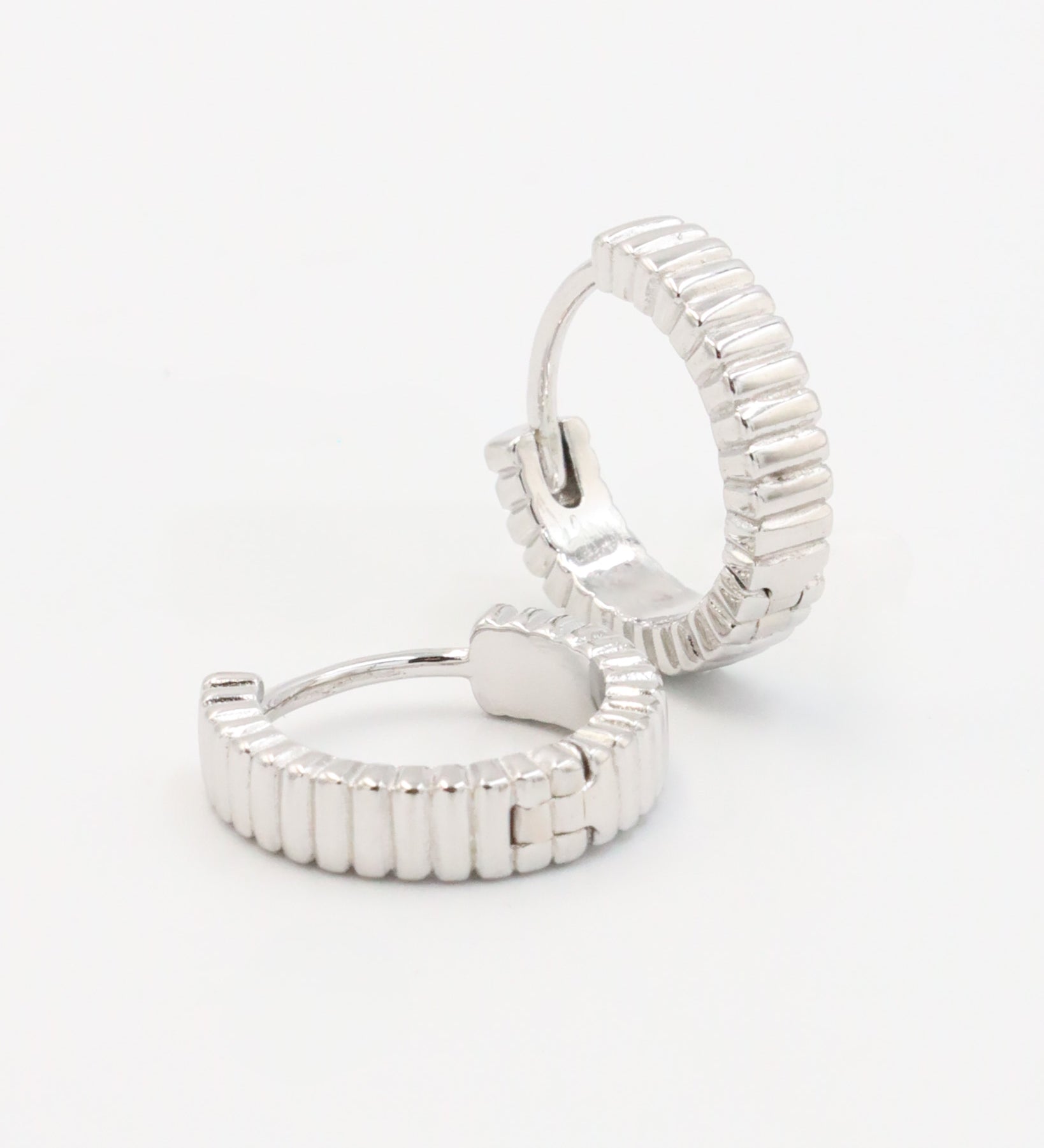 A pair of silver hoop earrings with a textured surface, displayed against a white background.