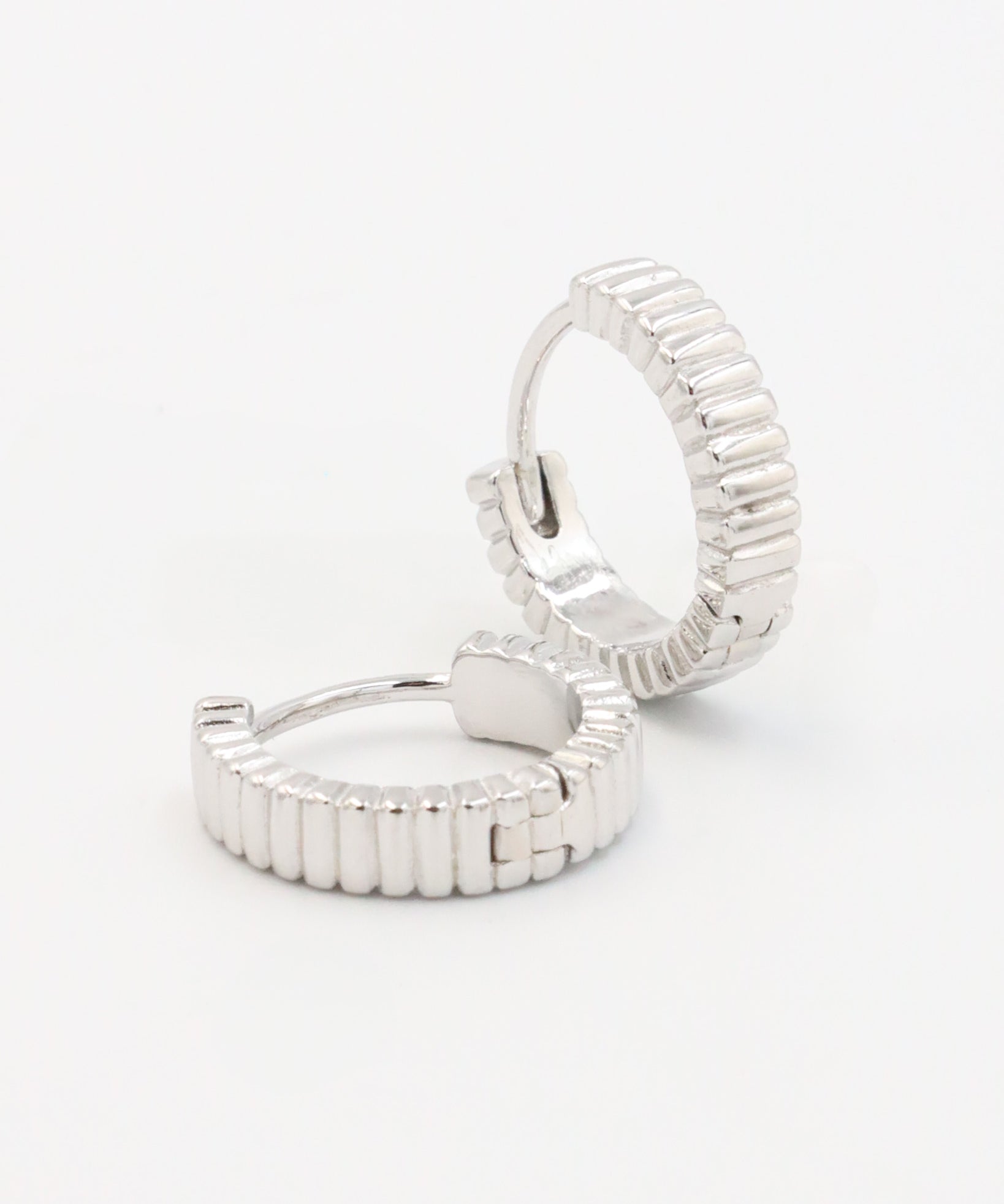 A pair of silver hoop earrings with a textured surface, displayed against a white background.
