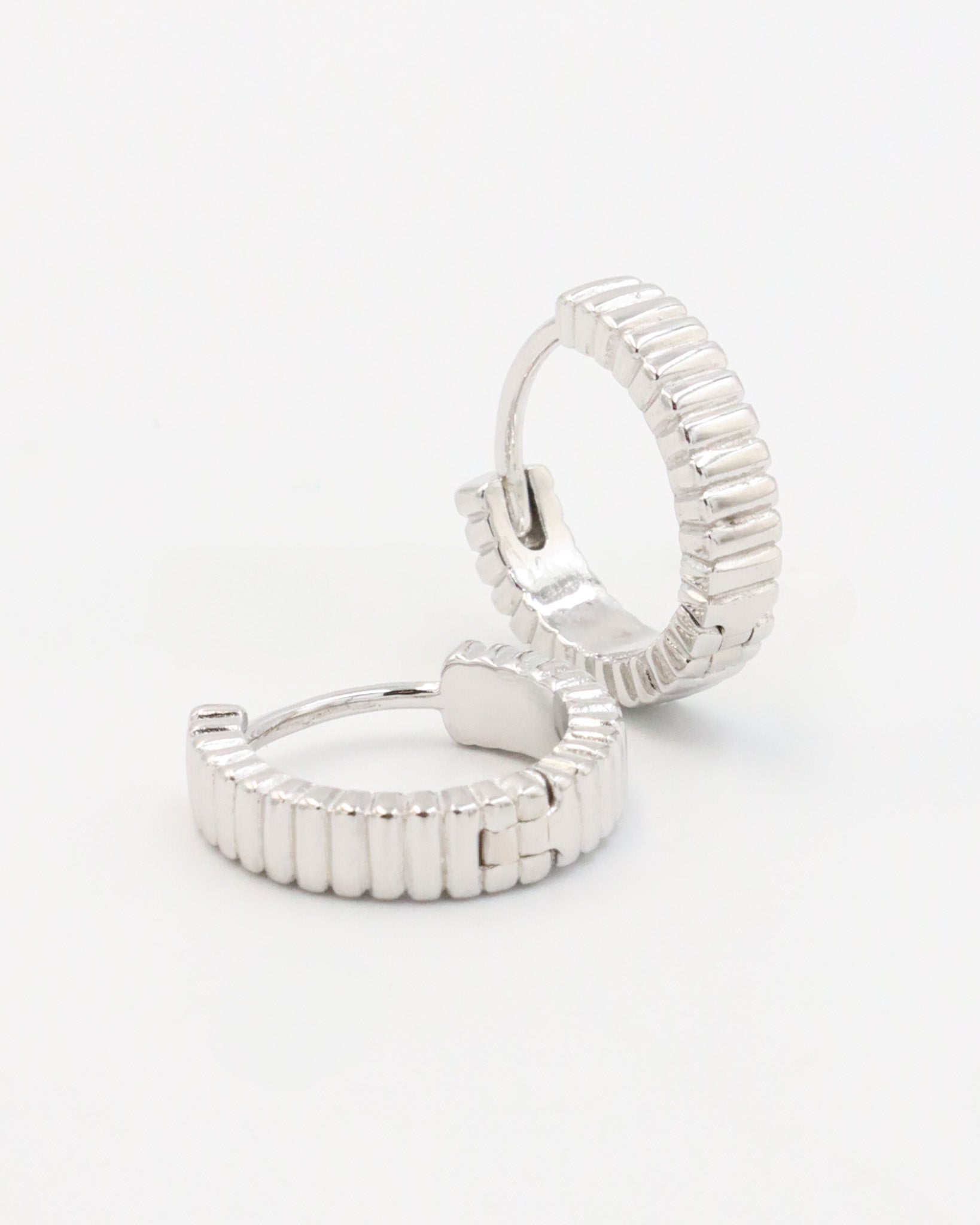 A pair of silver hoop earrings with a textured surface, displayed against a white background.