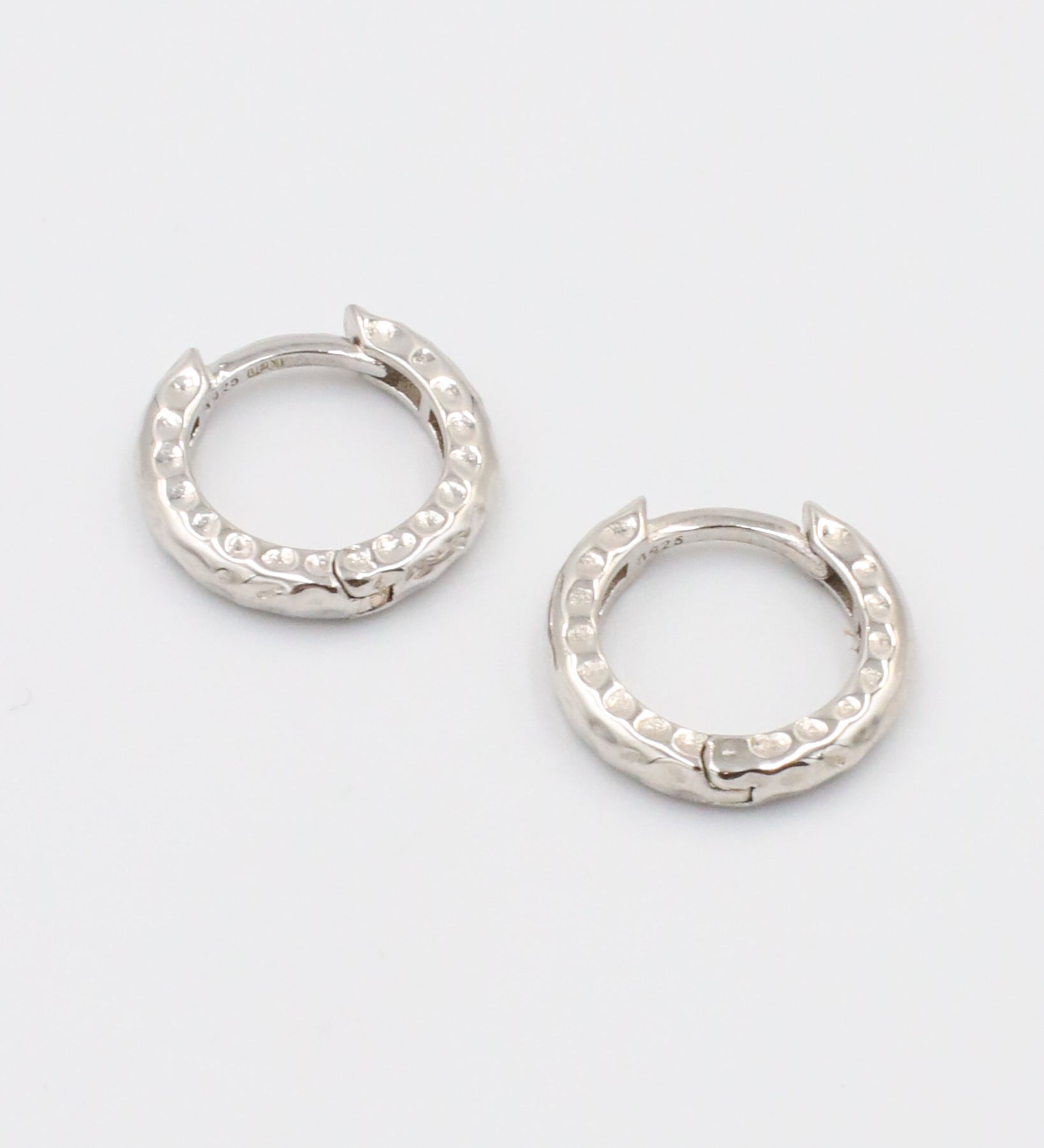 A pair of silver hoop earrings with a patterned design.