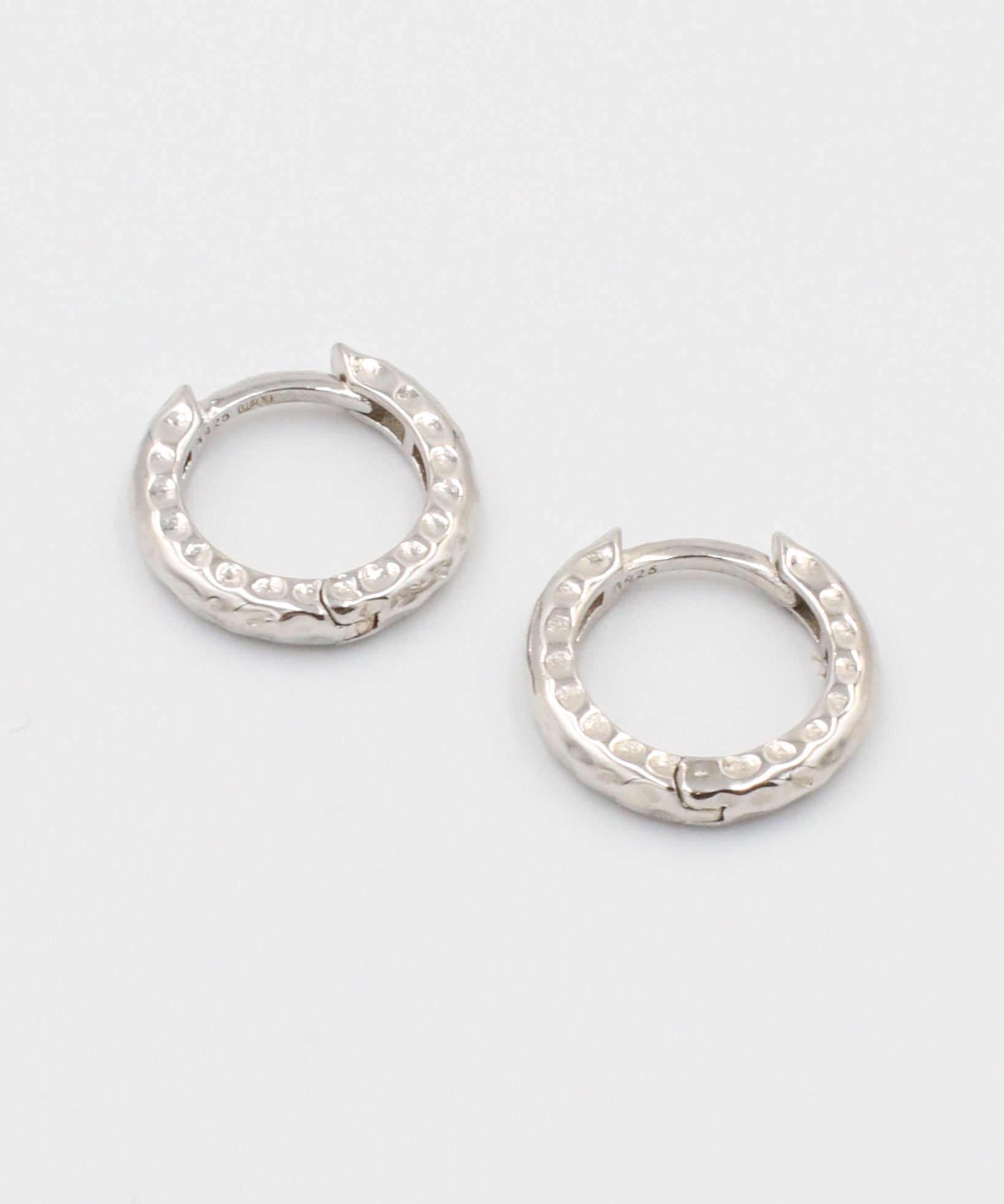 A pair of silver hoop earrings with a patterned design.