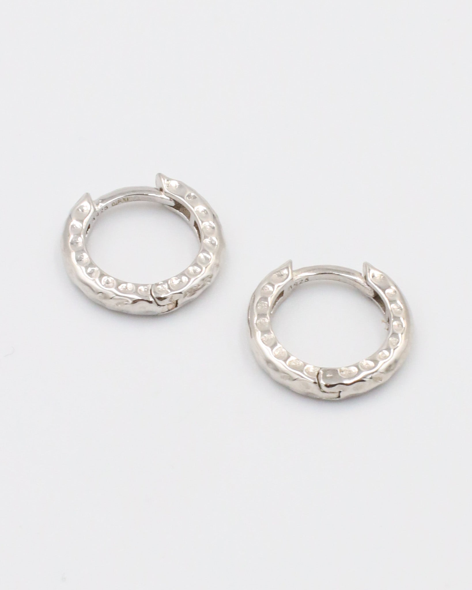 A pair of silver hoop earrings with a patterned design.