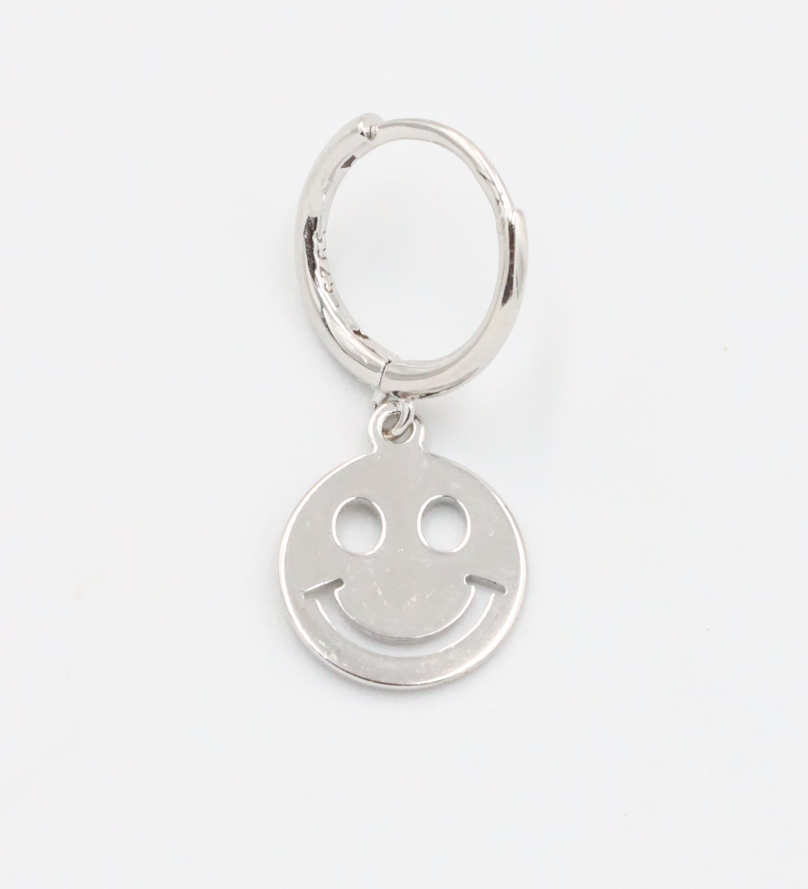 A silver hoop charm with a smiley face design on it.