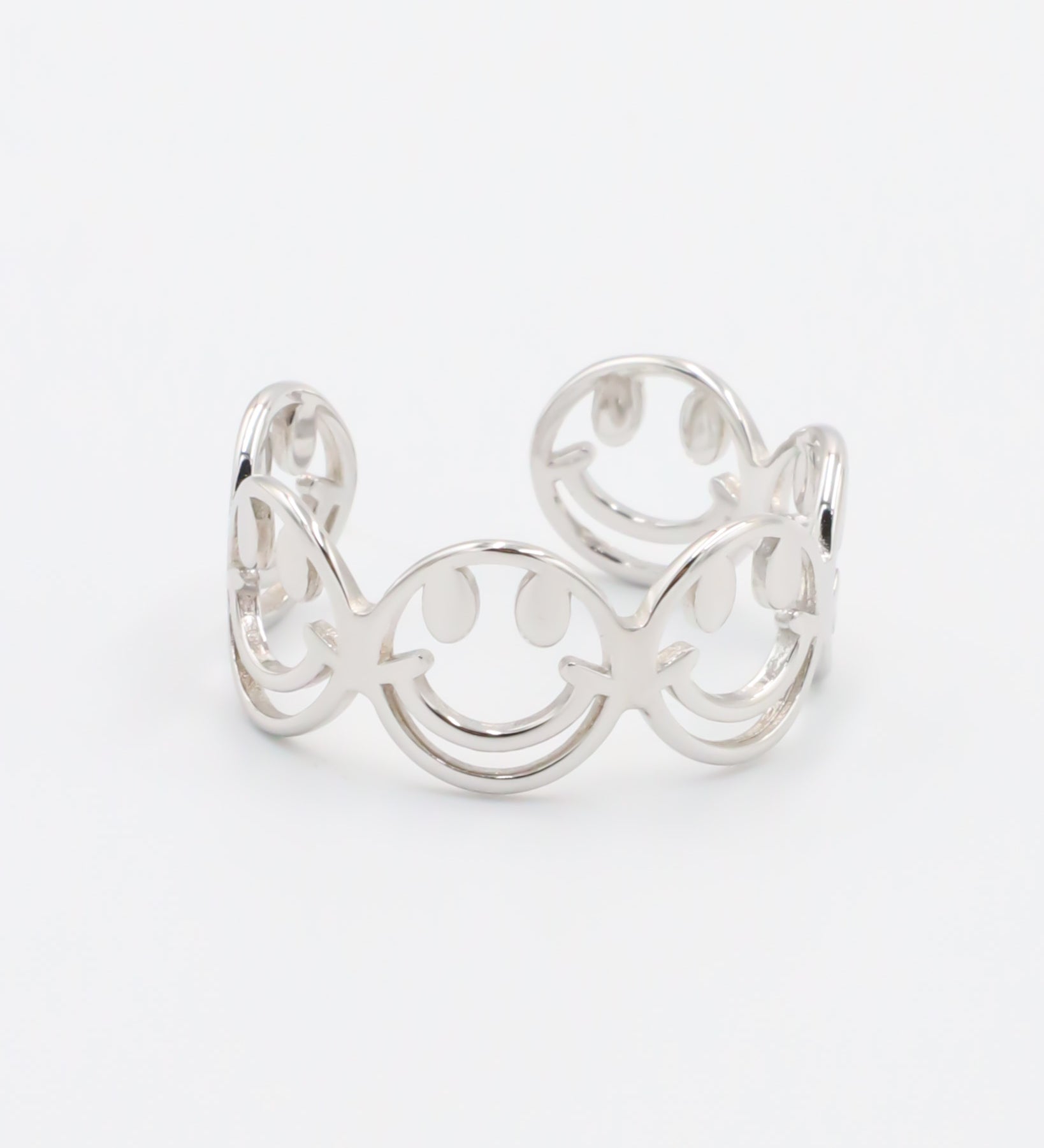 A silver ring with a design featuring multiple smiling face motifs.