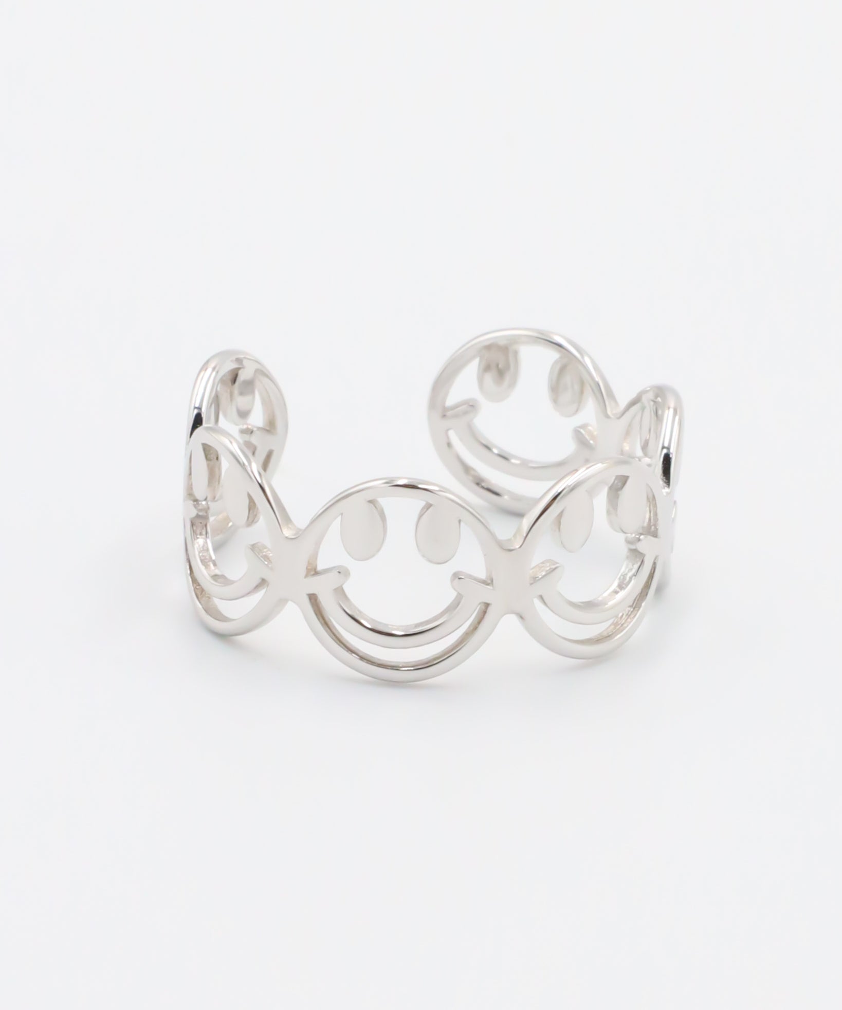 A silver ring with a design featuring multiple smiling face motifs.