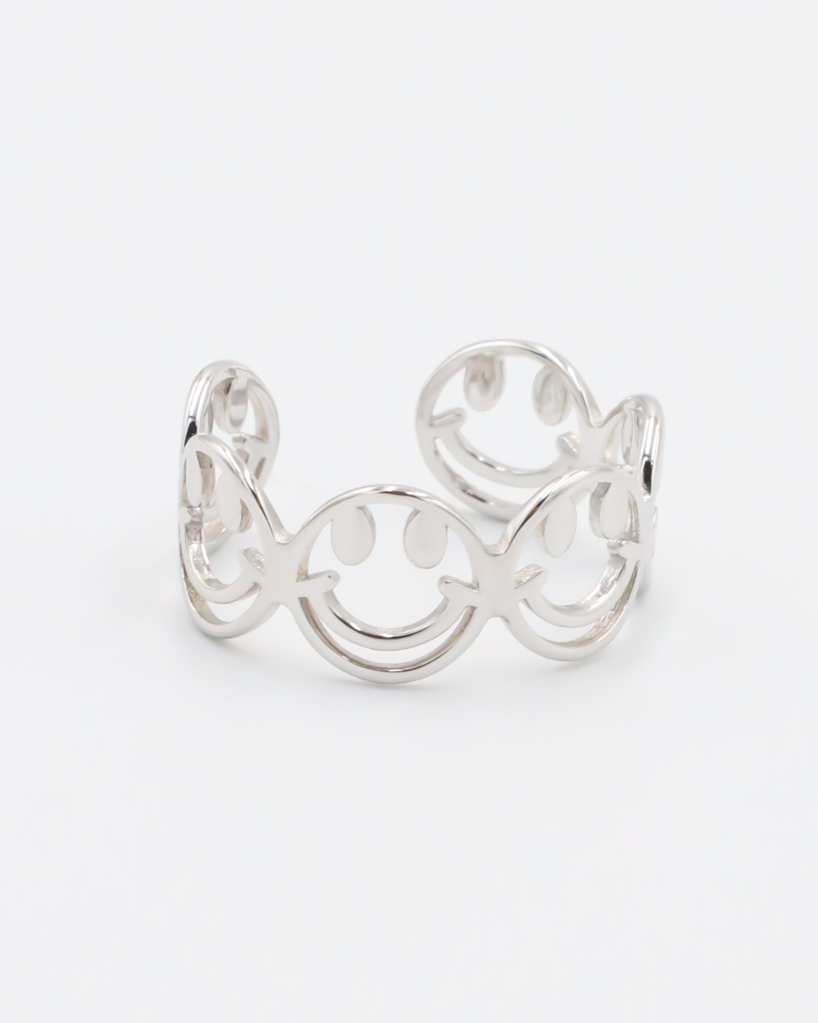 A silver ring with a design featuring multiple smiling face motifs.