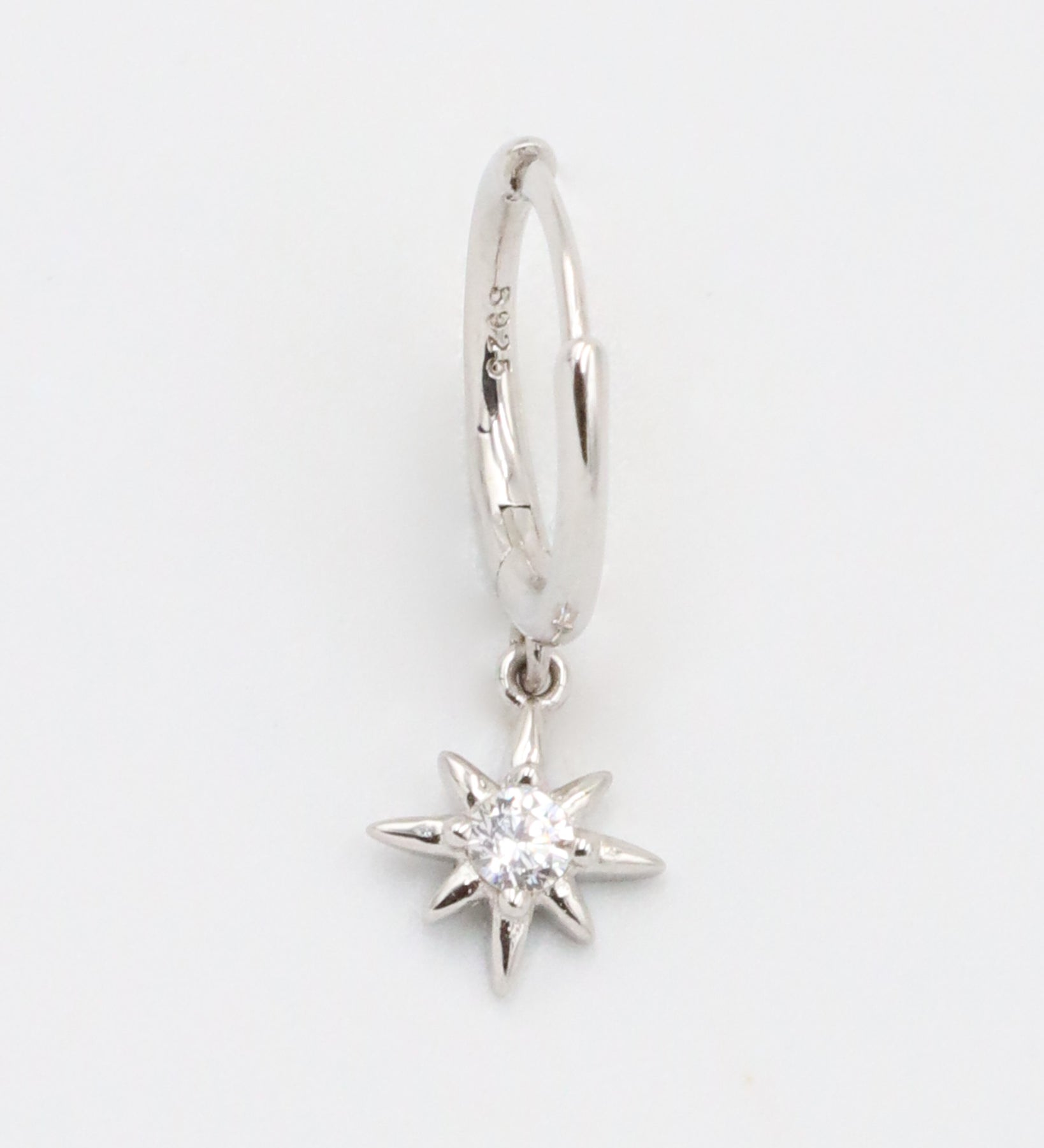 A silver hoop earring with a small star-shaped charm dangling from it.