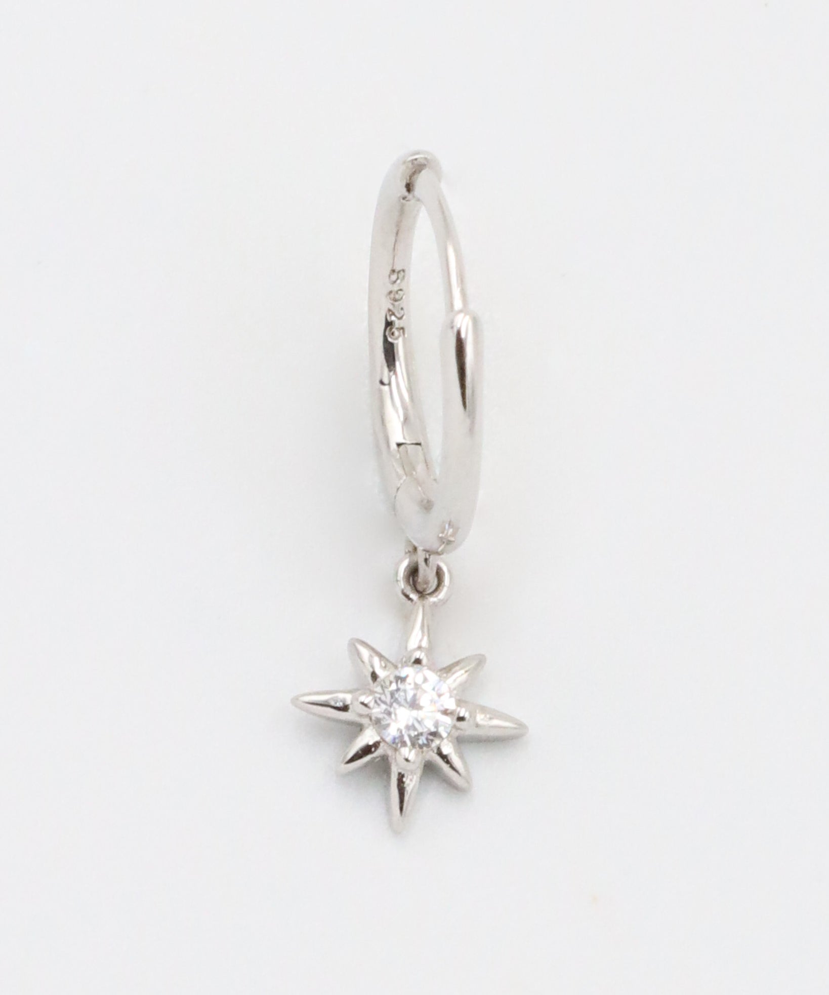 A silver hoop earring with a small star-shaped charm dangling from it.