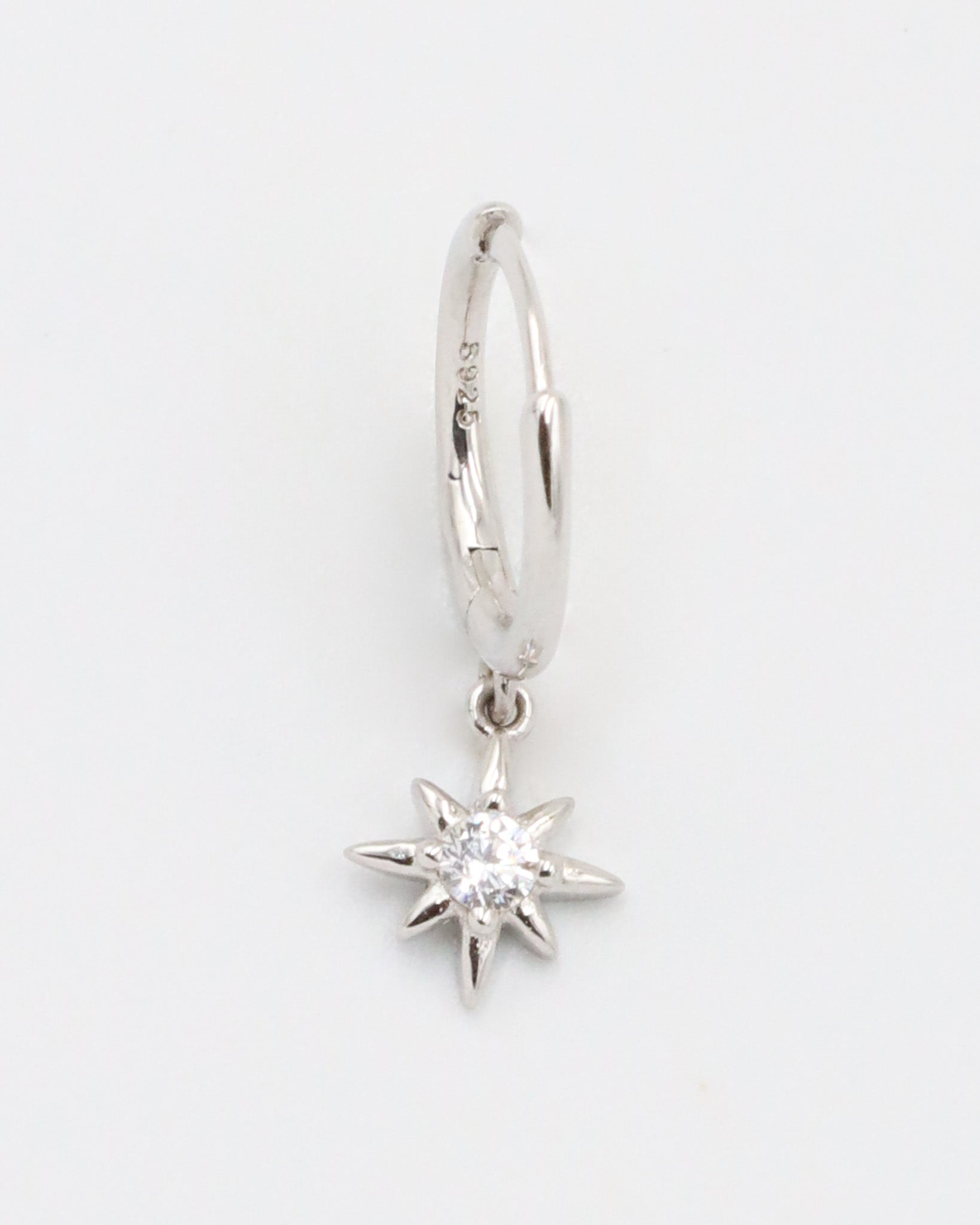 A silver hoop earring with a small star-shaped charm dangling from it.