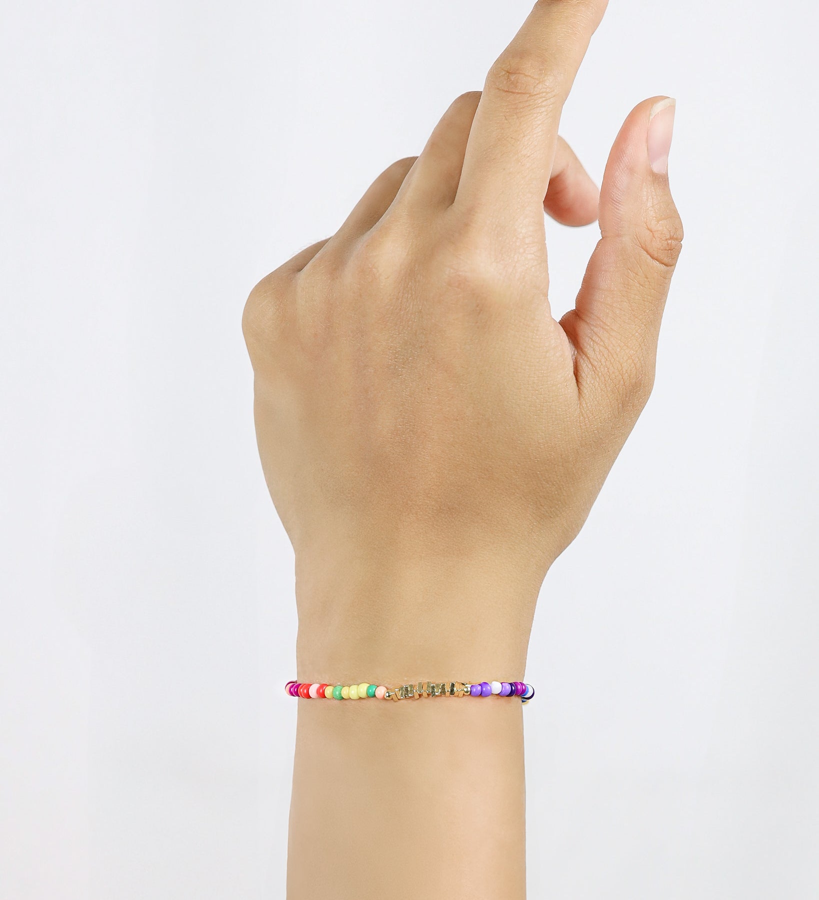 Hand wearing a colorful beaded bracelet on a plain background