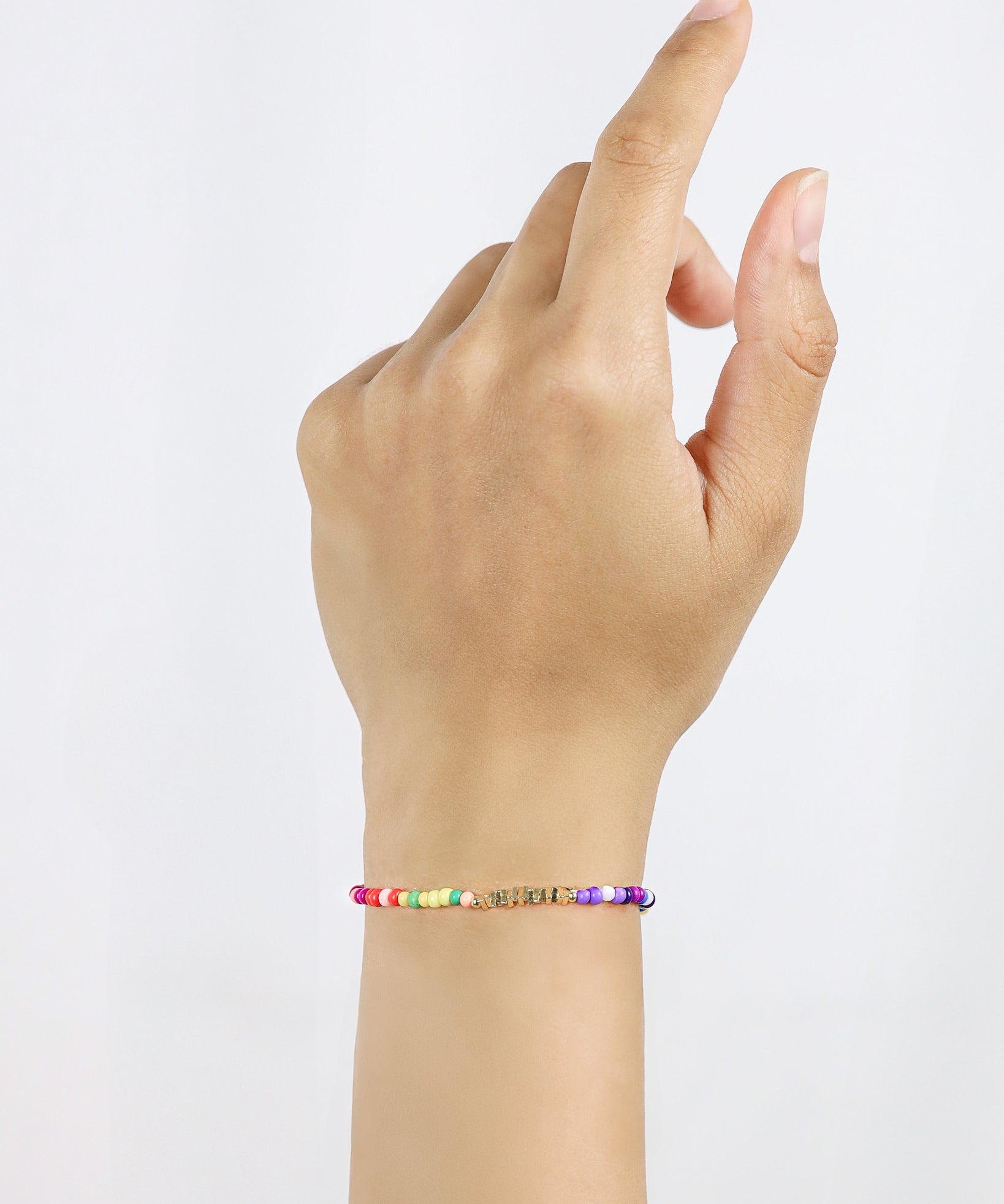 Hand wearing a colorful beaded bracelet on a plain background