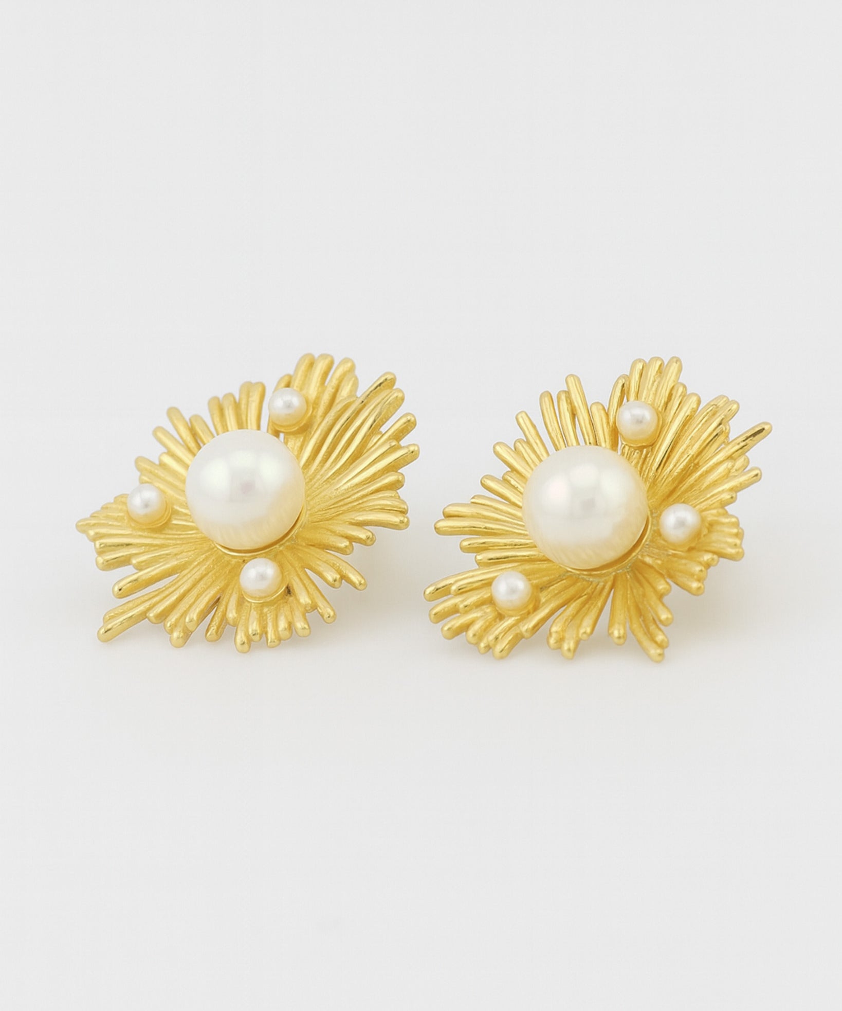 Gold earrings with pearl centers on a white background