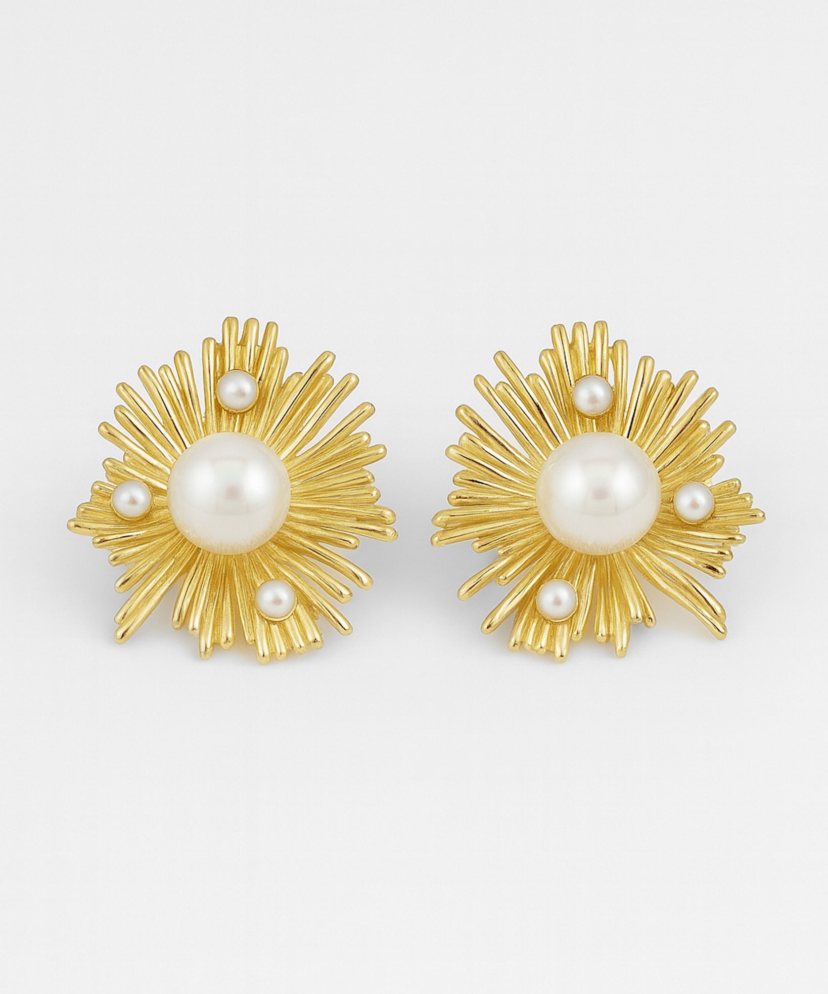 Gold earrings with pearl centers on a white background