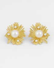 Gold earrings with pearl centers on a white background