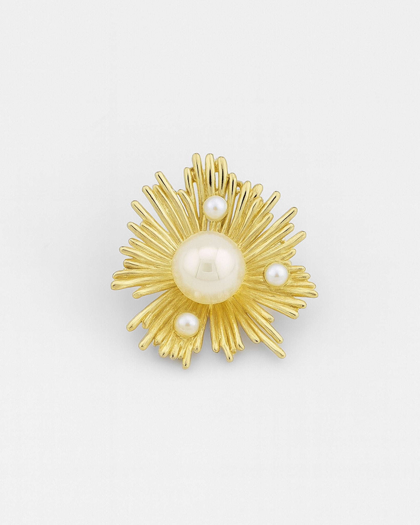 Gold brooch with pearl-like stones on a white background