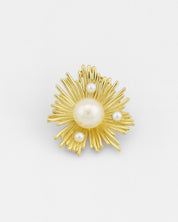 Gold brooch with pearl-like stones on a white background