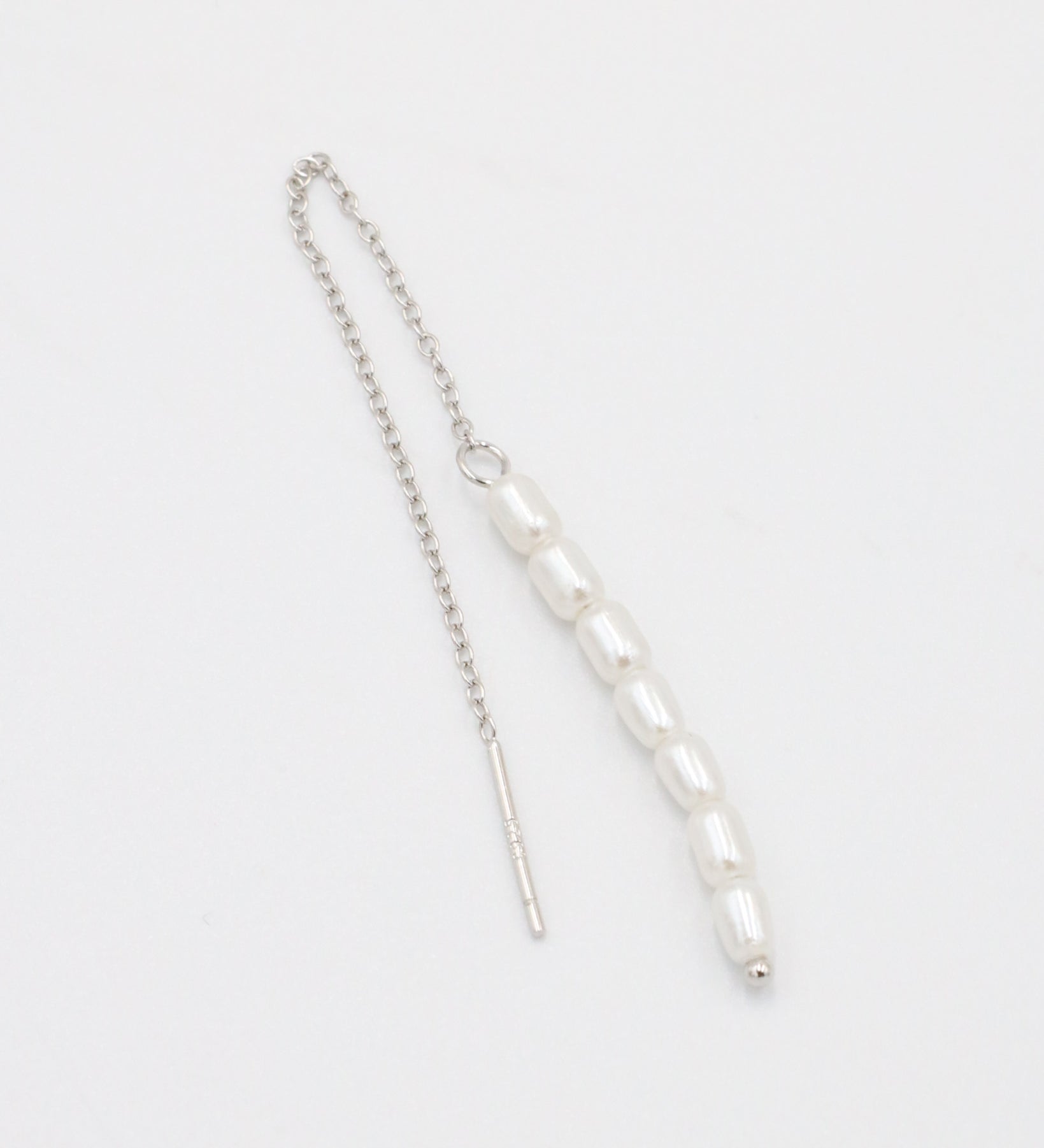 A silver necklace with two white beads on a chain, laid out against a white background.