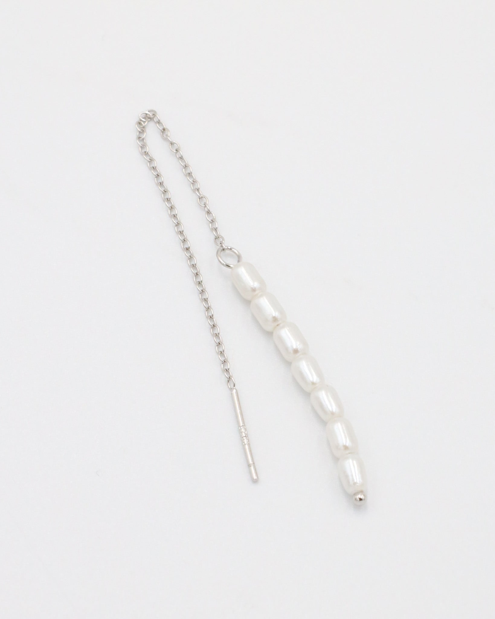 A silver necklace with two white beads on a chain, laid out against a white background.