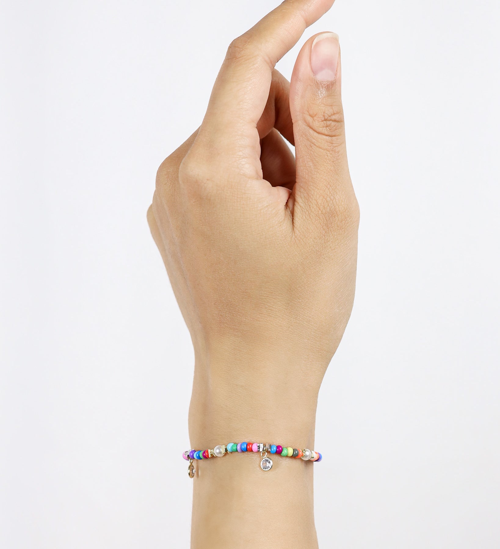 Hand wearing a colorful beaded bracelet on a light gray background