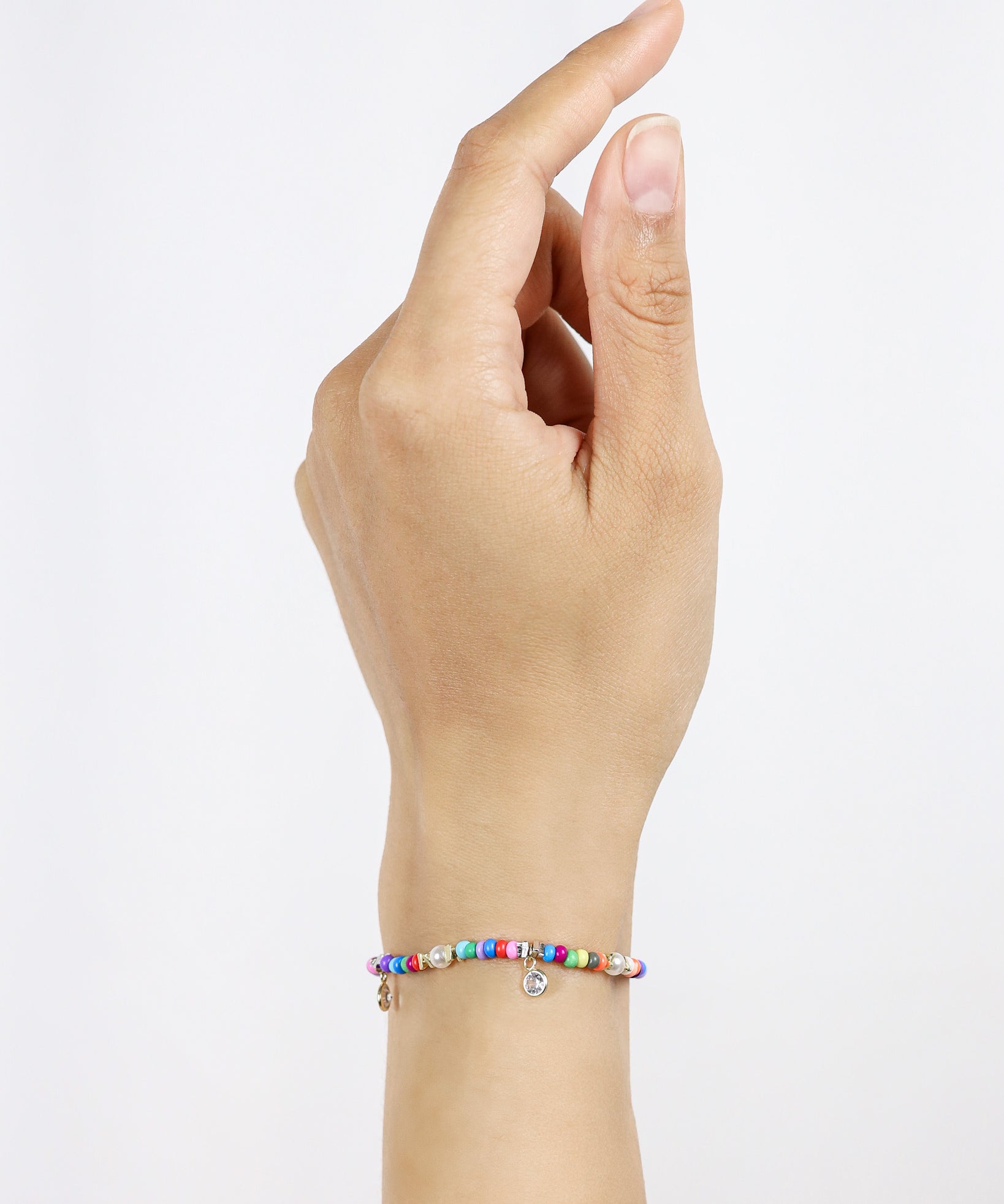 Hand wearing a colorful beaded bracelet on a light gray background