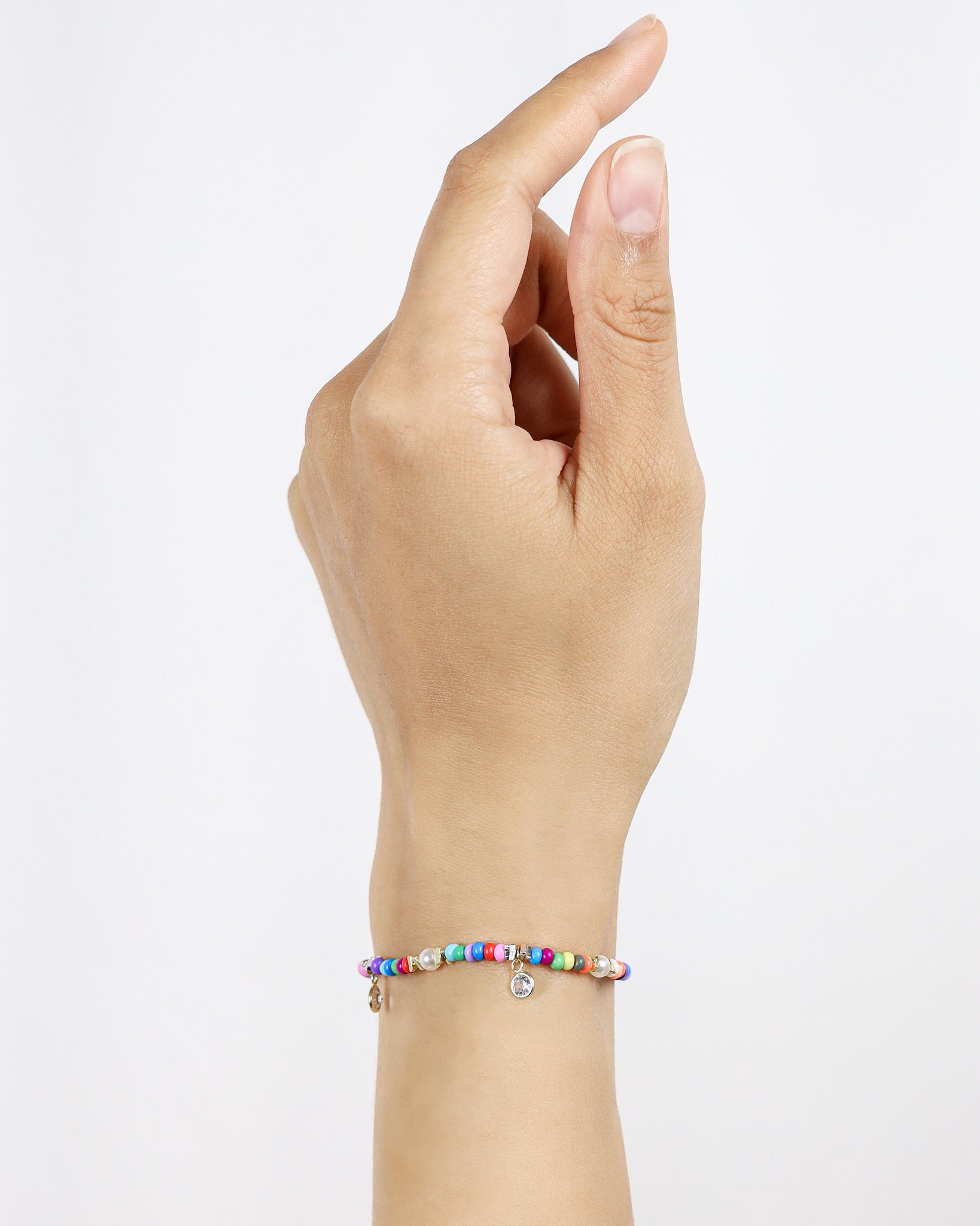 Hand wearing a colorful beaded bracelet on a light gray background
