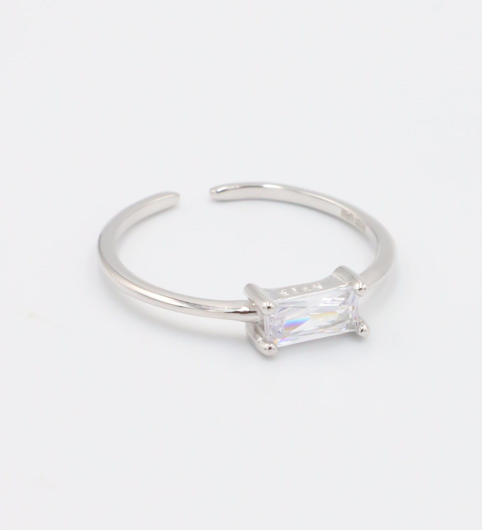 An adjustable silver ring with a clear central stone, on a white background.