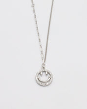 A silver necklace with a circular pendant featuring a smiley face design, displayed against a white background.