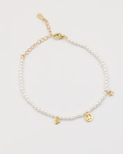 A gold-colored bracelet with white pearl beads and decorative gold beads, featuring a star and a heart charm.