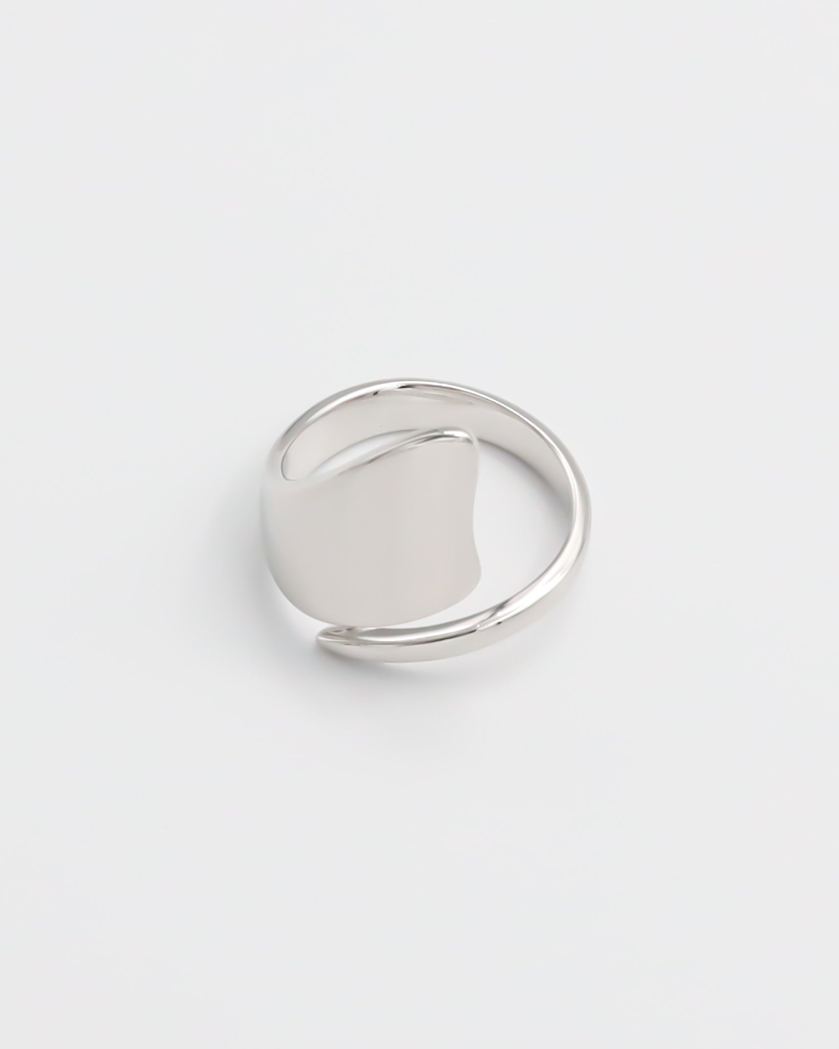 A silver ring with an abstract design on a white background.
