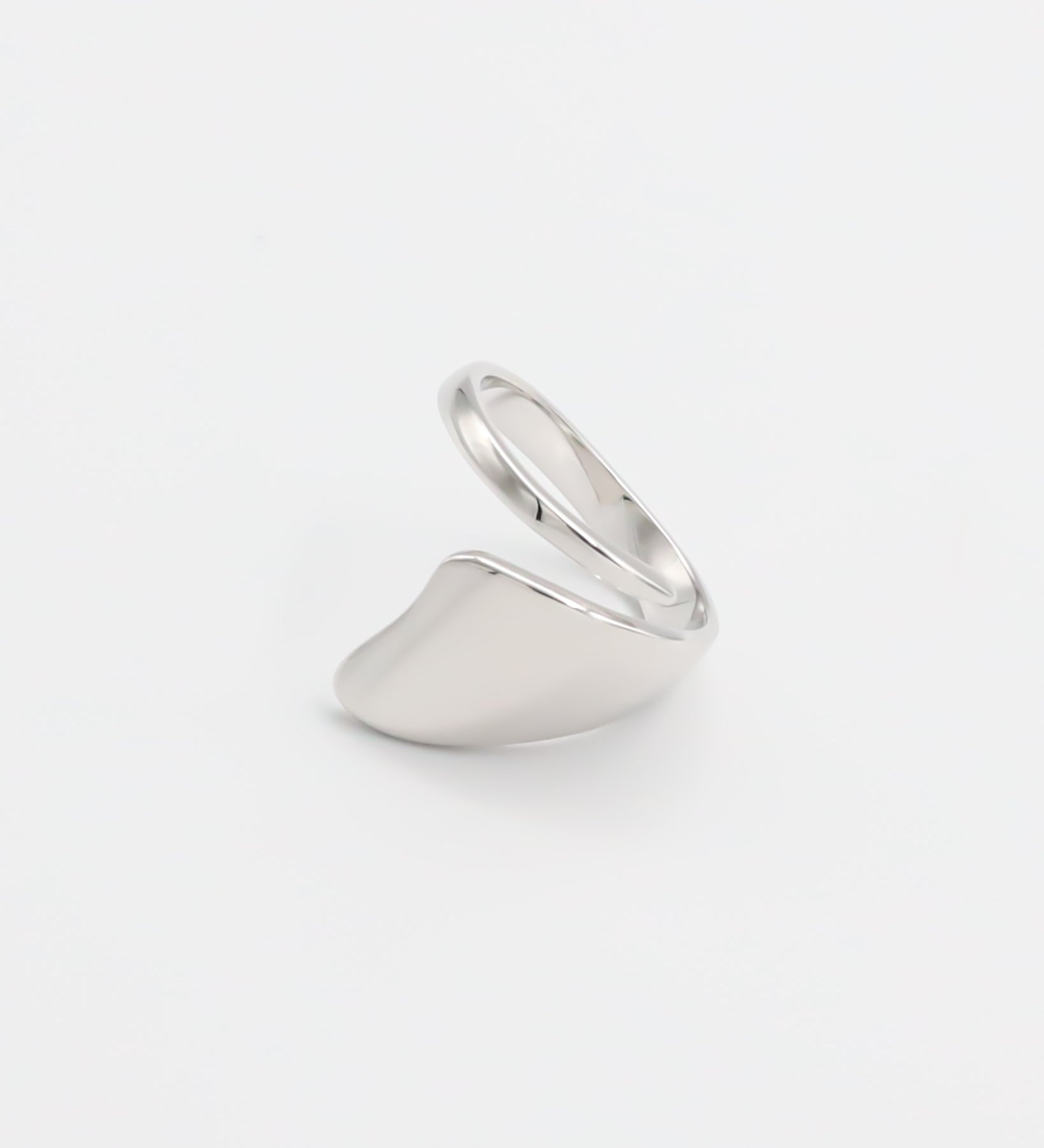 A silver ring with an abstract design on a white background.