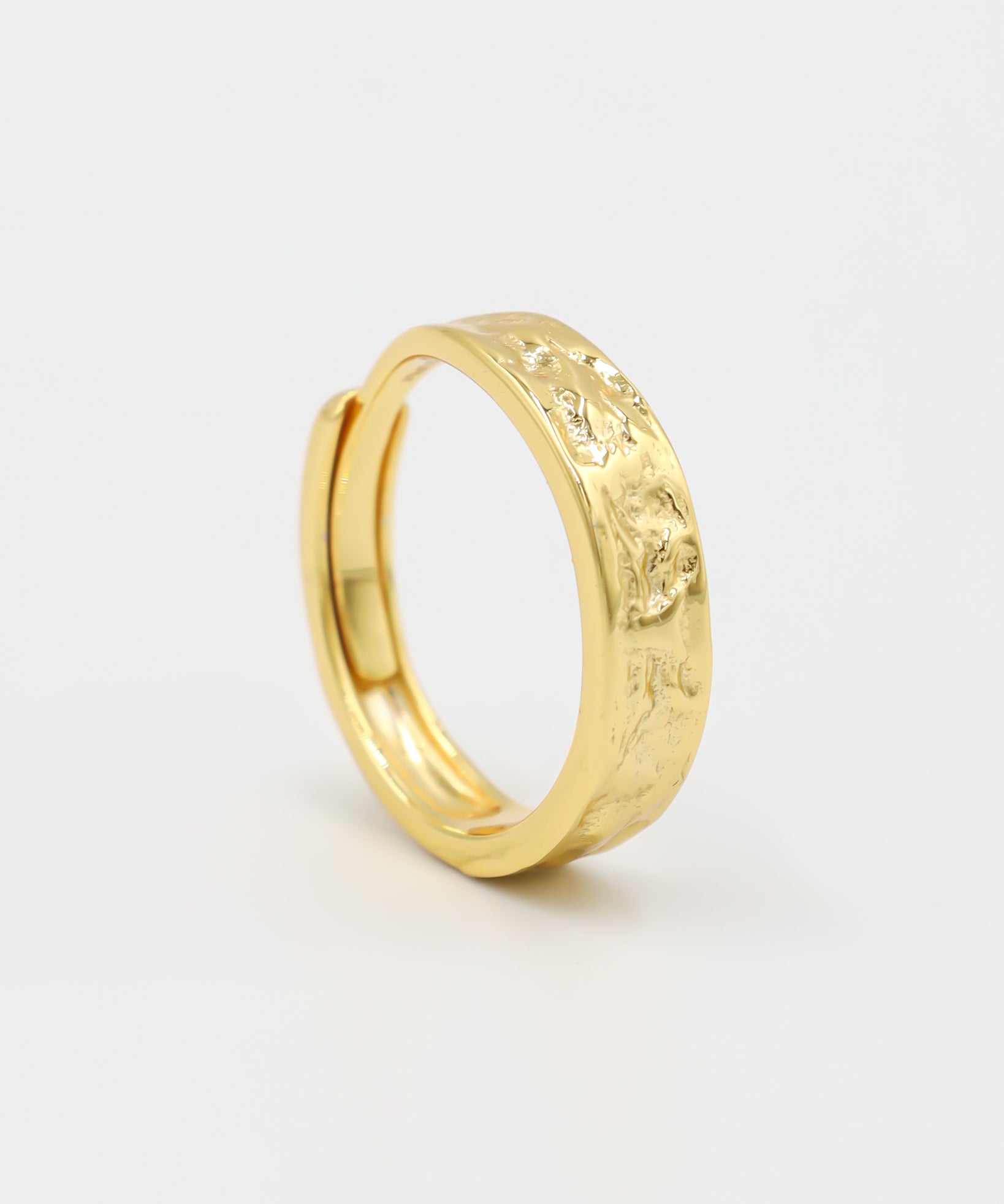 A gold-colored ring with intricate designs on the top surface, displayed against a white background.