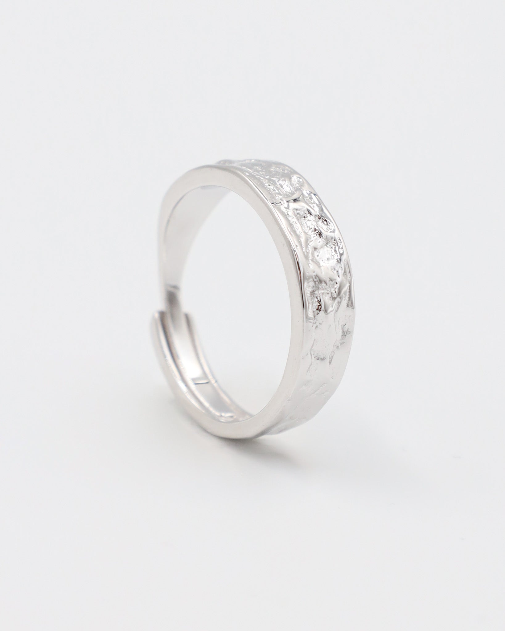 A simple silver ring with a textured surface, displayed against a white background.