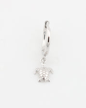 Silver hoop earring with a turtle charm on a white background