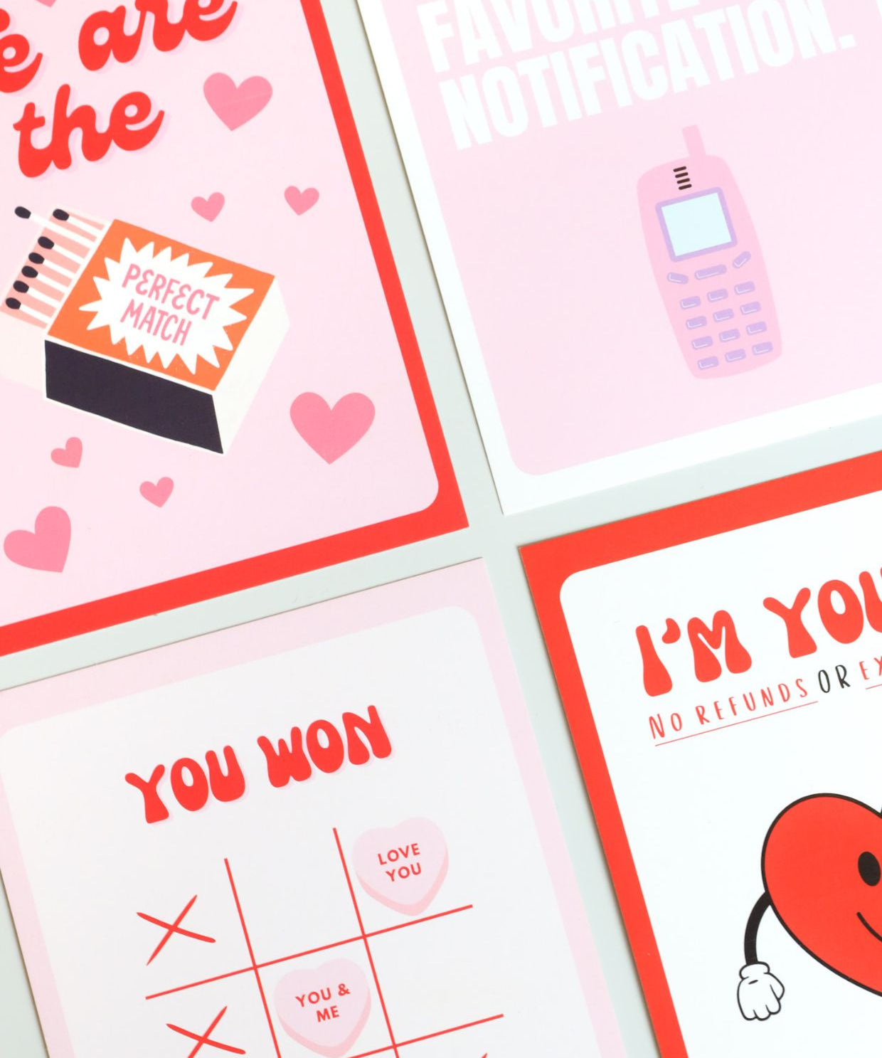 Four playful Valentine’s Day postcards in a bold, pop-art style: one with a matchbox reading “Perfect Match” surrounded by hearts, one saying “You’re my favorite notification” with a retro mobile phone, one with “You won” and a Tic-Tac-Toe layout using candy hearts, and one featuring a smiling heart with the phrase “I’m yours – no refunds.” 