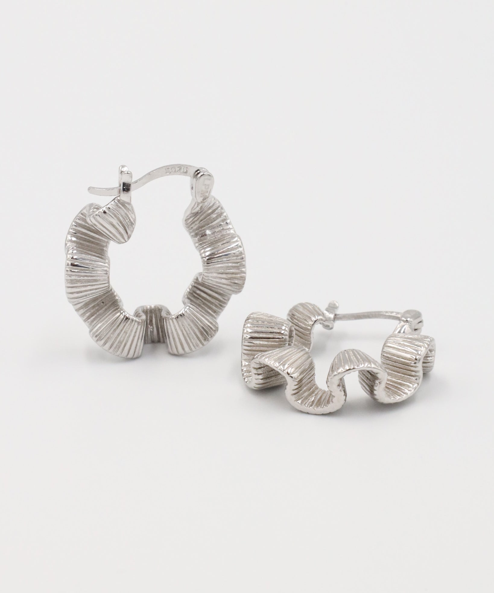 A pair of silver creole earrings with a latch back clasp, displayed against a white background.