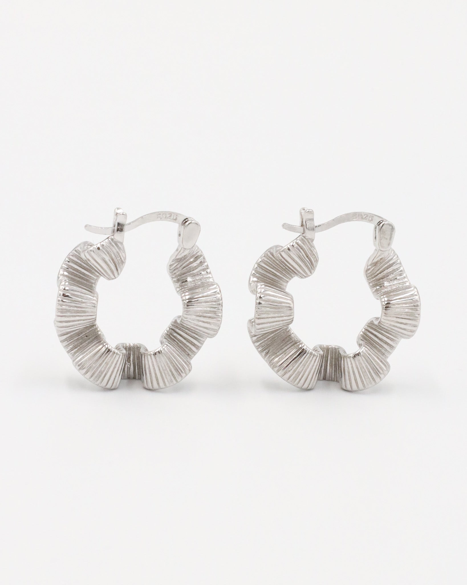 A pair of silver creole earrings with a latch back clasp, displayed against a white background.