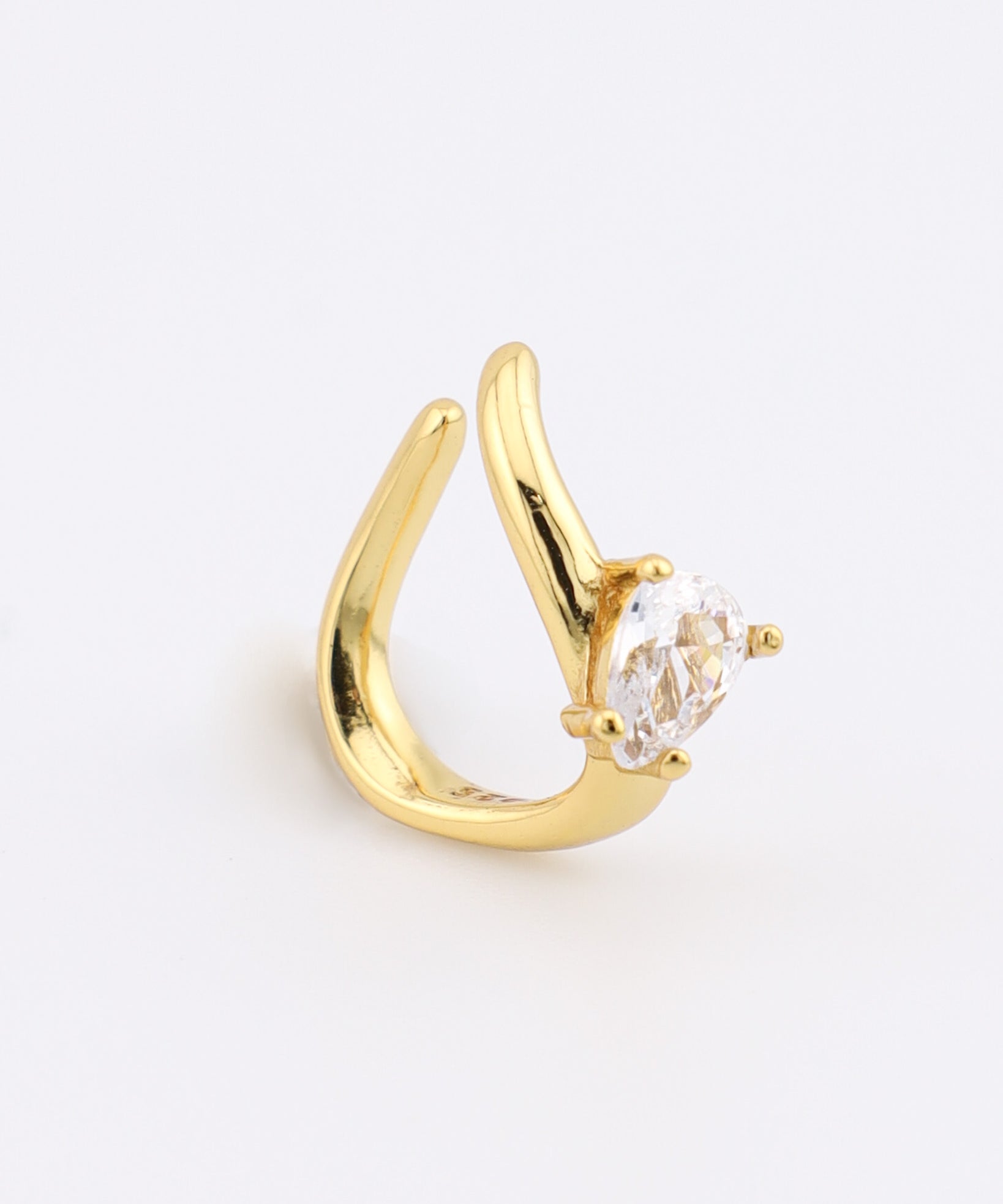 Gold earring with a clear gemstone on a light gray background