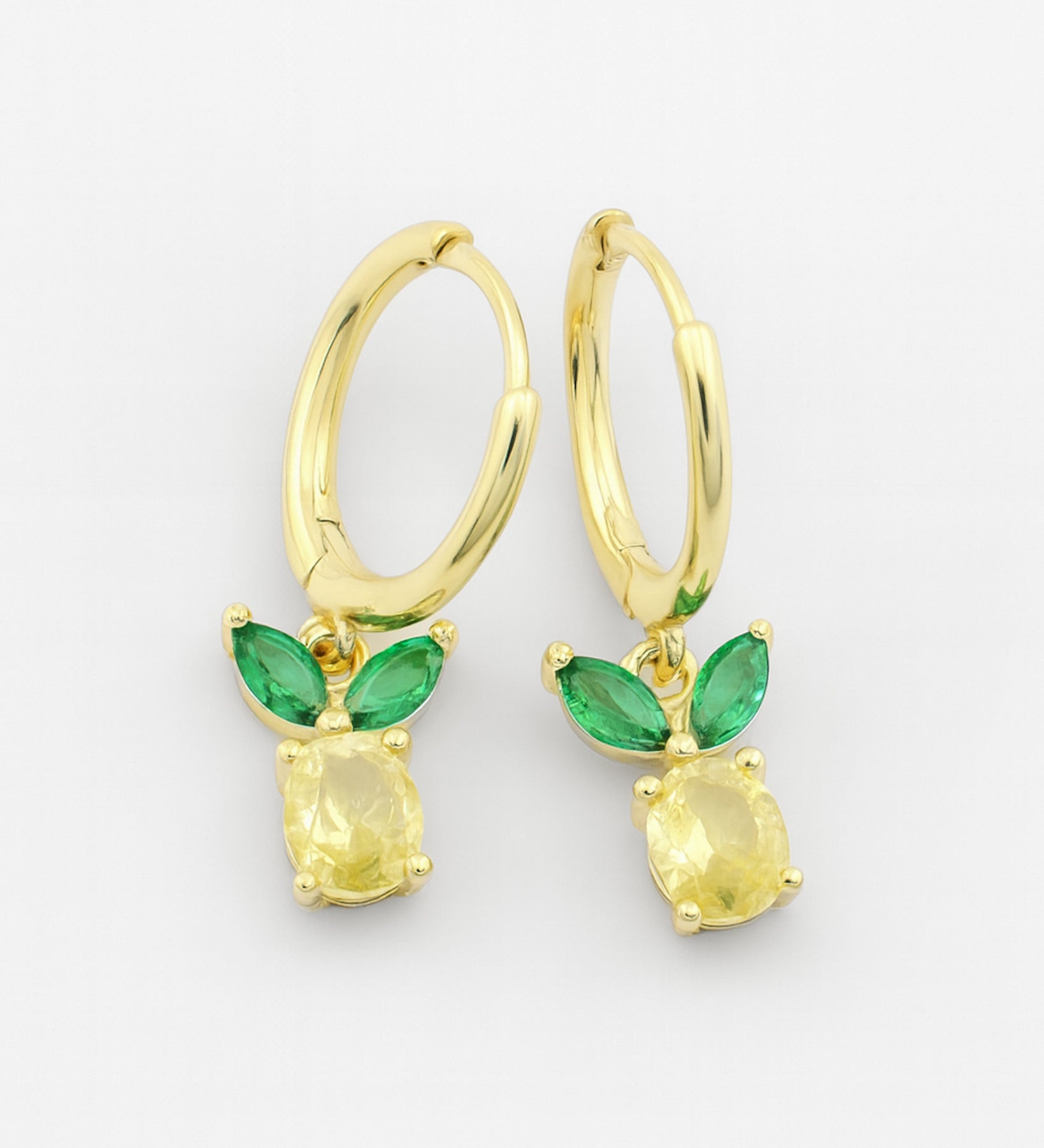 Gold earrings with green gemstones on a white background