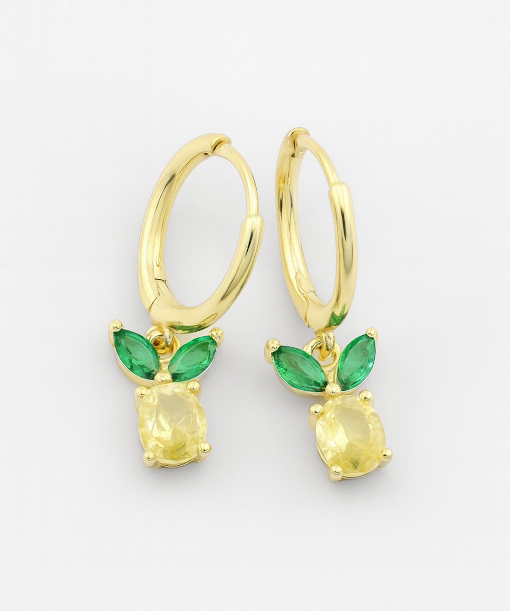 Gold earrings with green gemstones on a white background